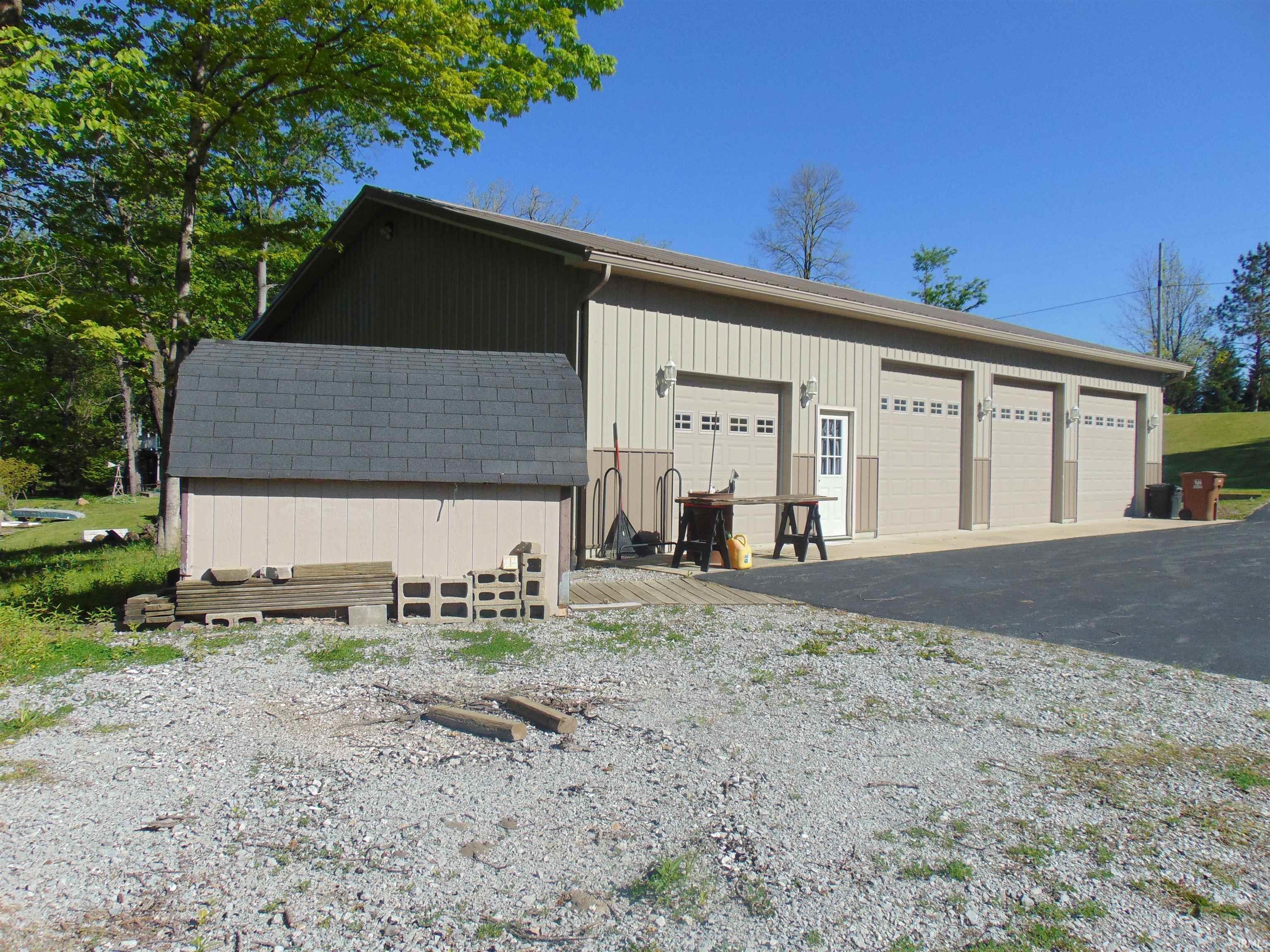 Image 2: Metal-sided outbuilding featuring three garage doors with window inserts and an entry door, Garage Image 2: Metal-sided outbuilding featuring three garage doors with window inserts and an entry door, Garage