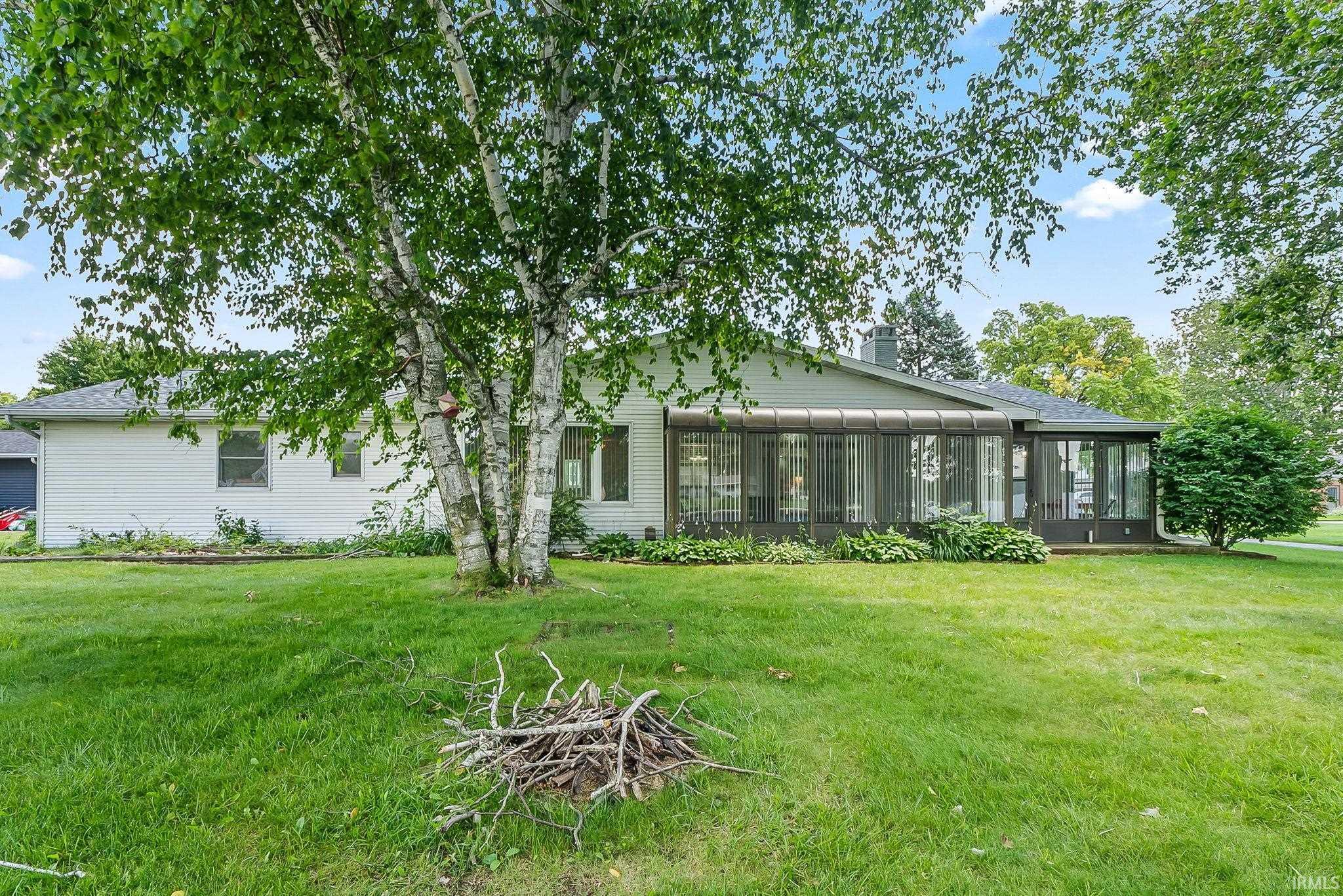 Image 2: Expansive rear yard featuring a sunroom addition with large windows, mature trees, and a manicured lawn, Back Of Structure