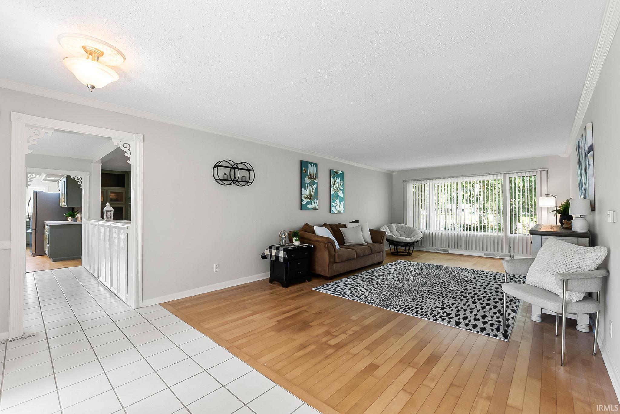 Image 3: Living area featuring light wood-finish flooring and a large window with vertical blinds, Living Room