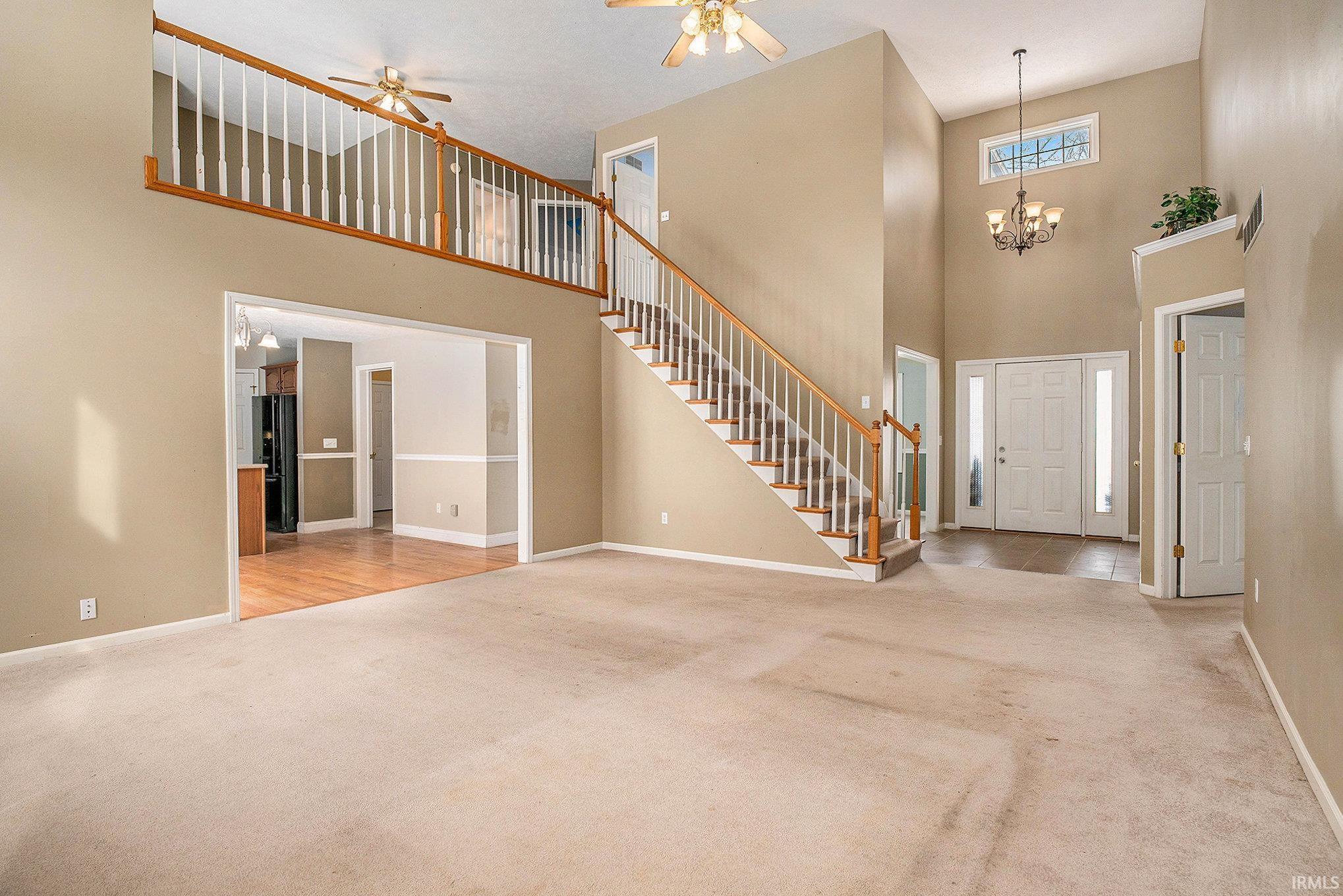 Image 1: Entrance foyer featuring a towering ceiling, light carpet, a chandelier, and a ceiling fan, Entrance Foyer