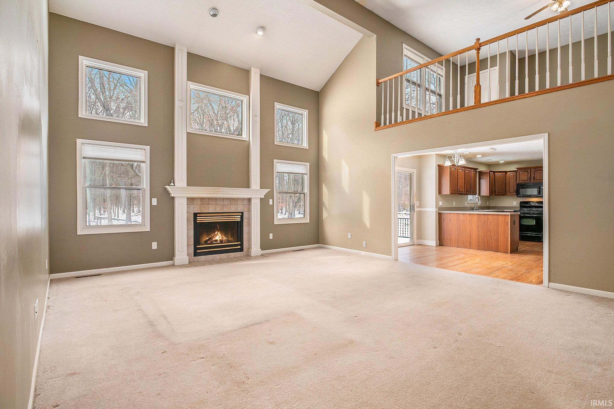 Image 2: Unfurnished living room with light colored carpet, a tile fireplace, plenty of natural light, and a high ceiling, Living Room