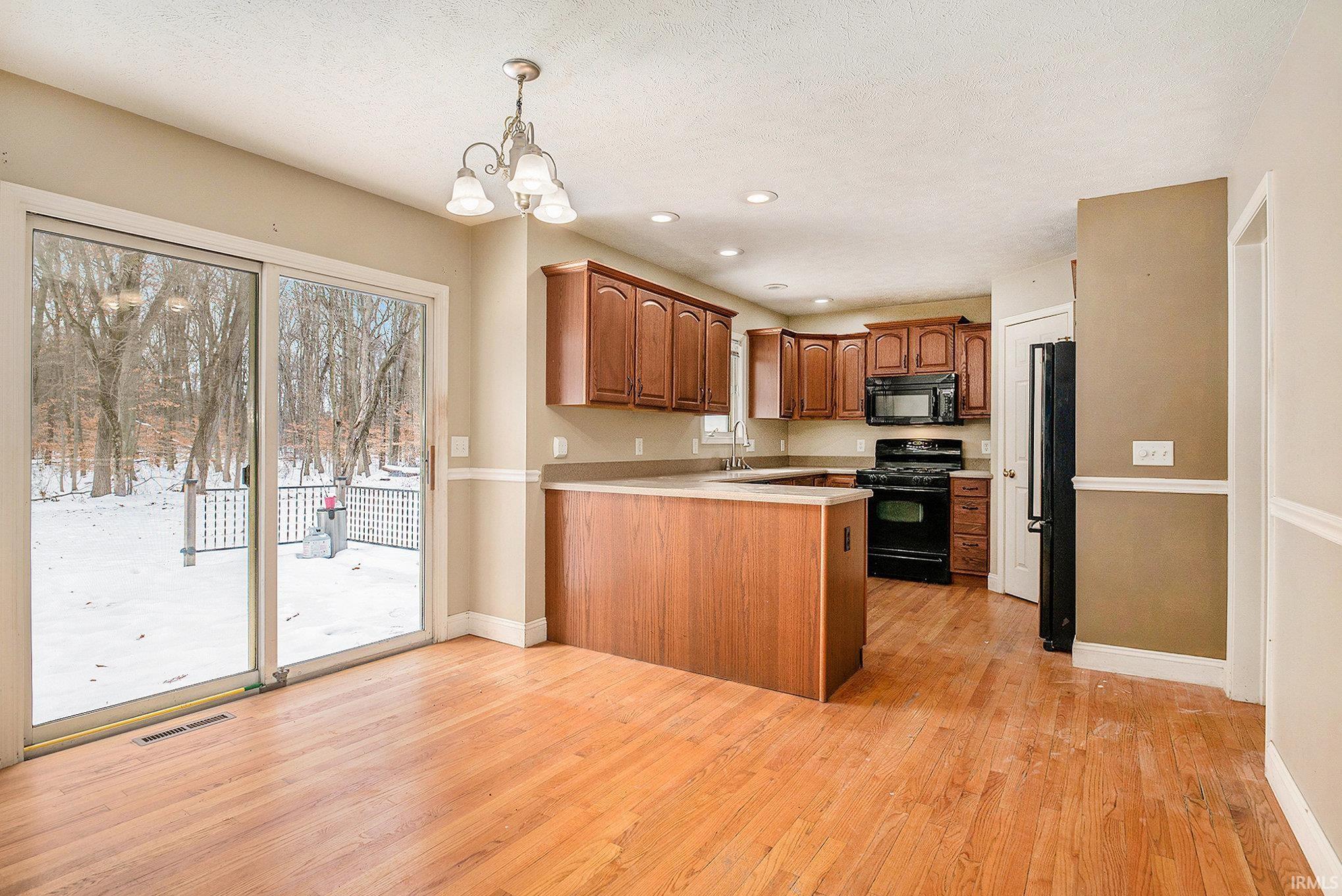 Image 3: Kitchen featuring black appliances, light countertops, brown cabinets, decorative light fixtures, and recessed lighting, Kitchen