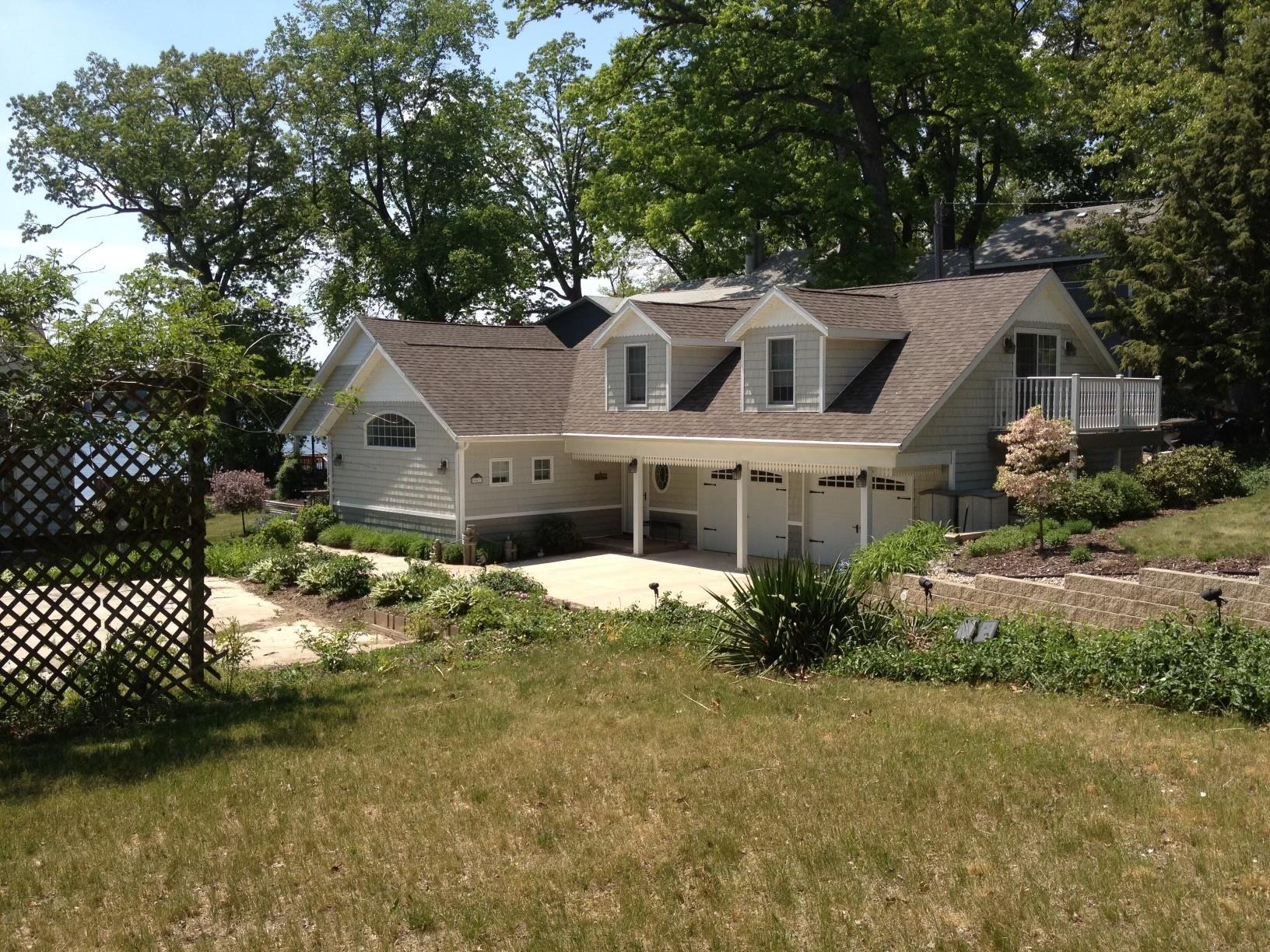 Image 0: Back of house featuring a yard, roof with shingles, and a garage, View - Primary Side