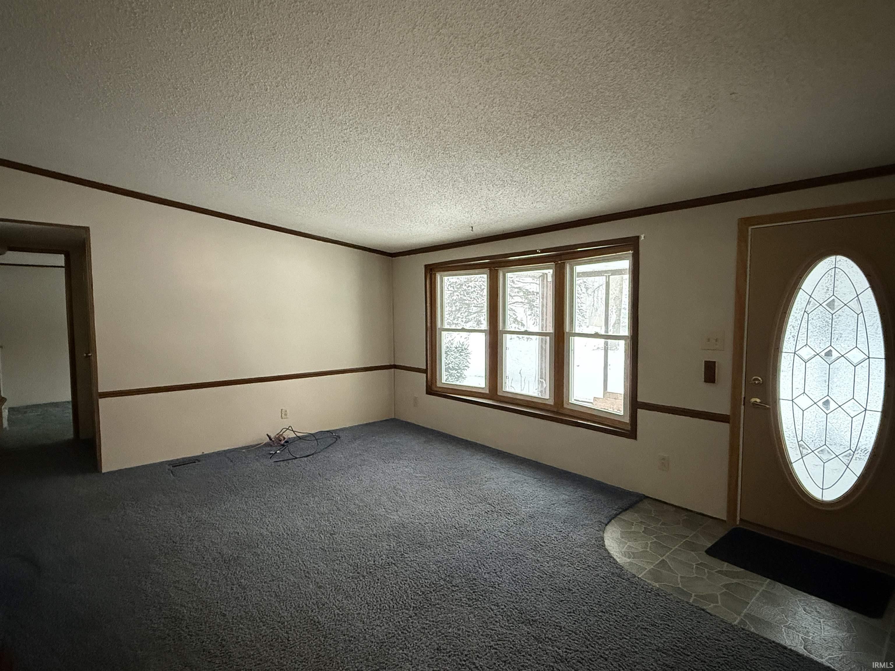 Image 1: Carpeted entrance foyer featuring a textured ceiling and crown molding, Living Room
