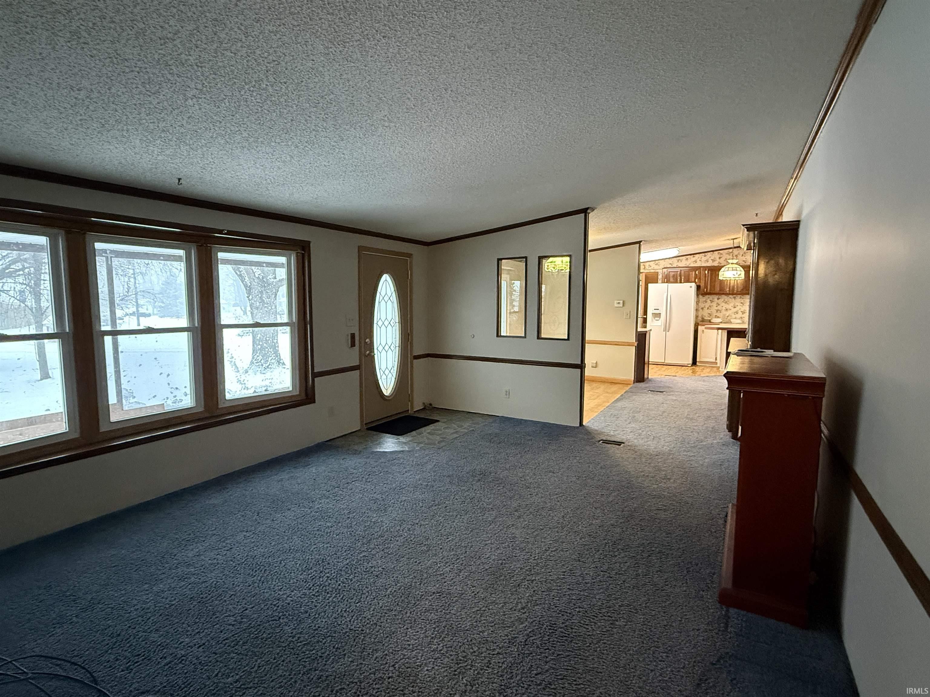 Image 2: Carpeted foyer with crown molding, a textured ceiling, and lofted ceiling, Living Room