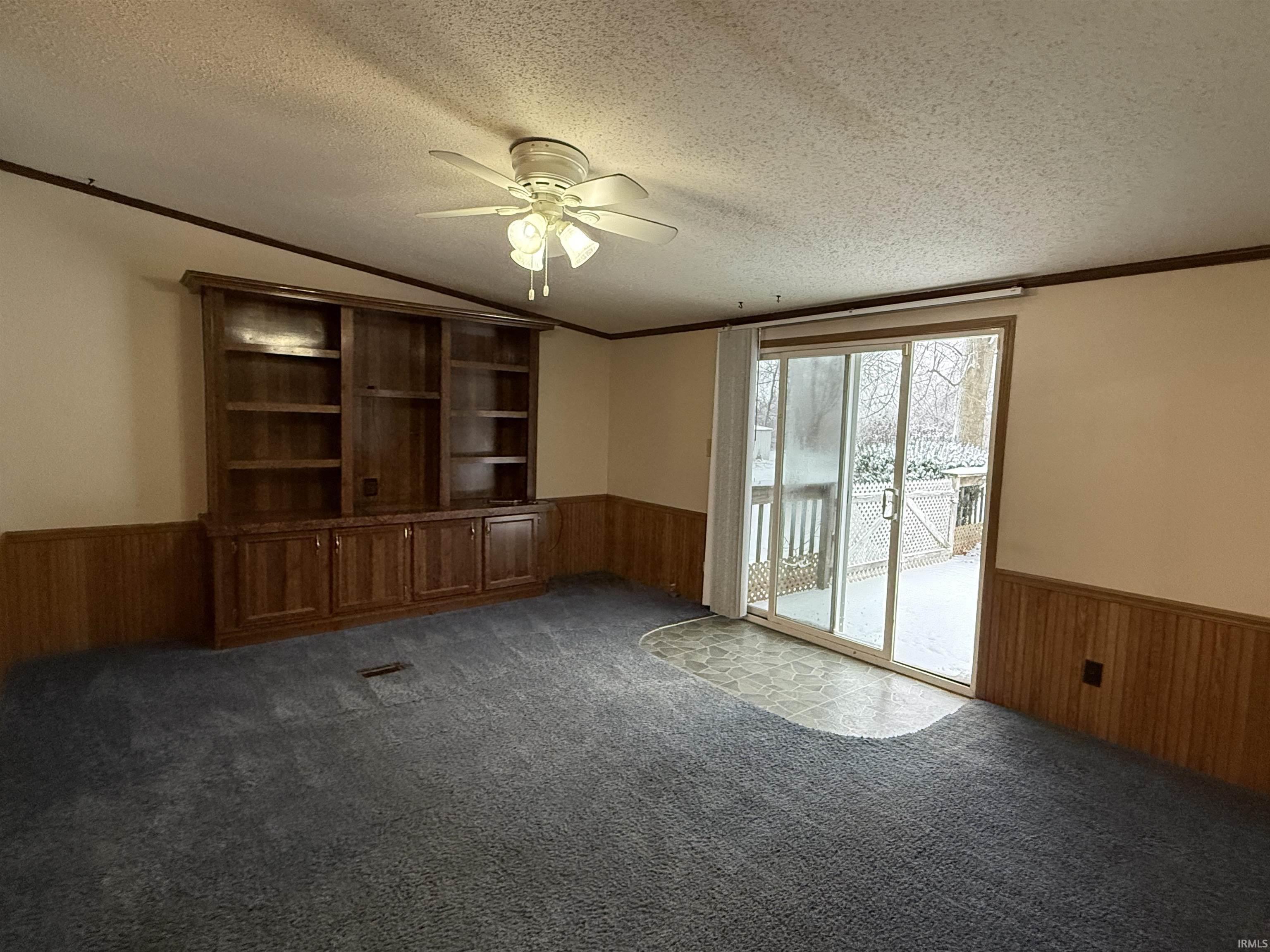 Image 3: Empty room featuring wooden walls, a wainscoted wall, ornamental molding, a ceiling fan, and dark carpet, Dining Room