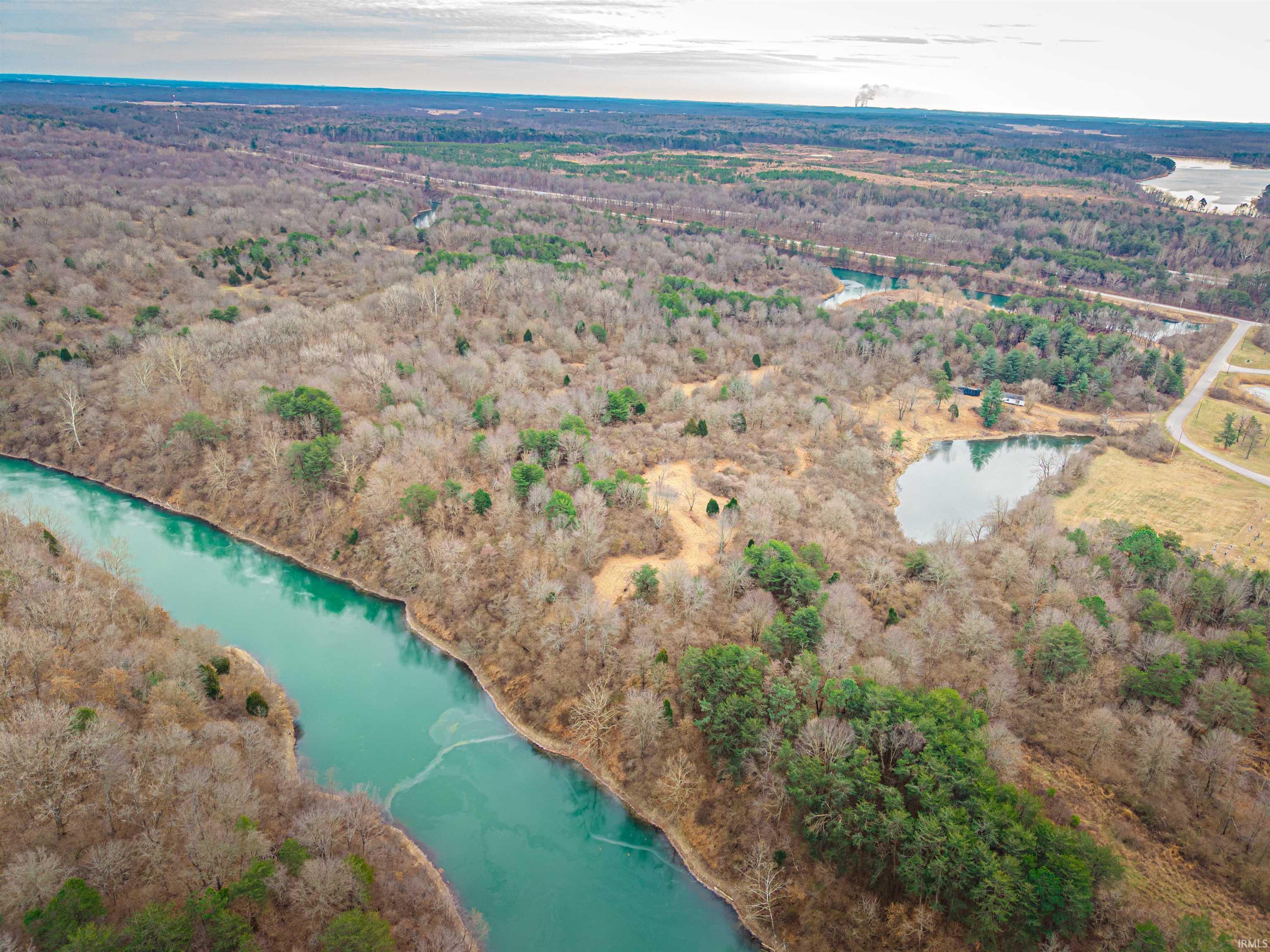 Image 1: Aerial overview of property's location with a nearby body of water and a forest, Aerial View Image 1: Aerial overview of property's location with a nearby body of water and a forest, Aerial View