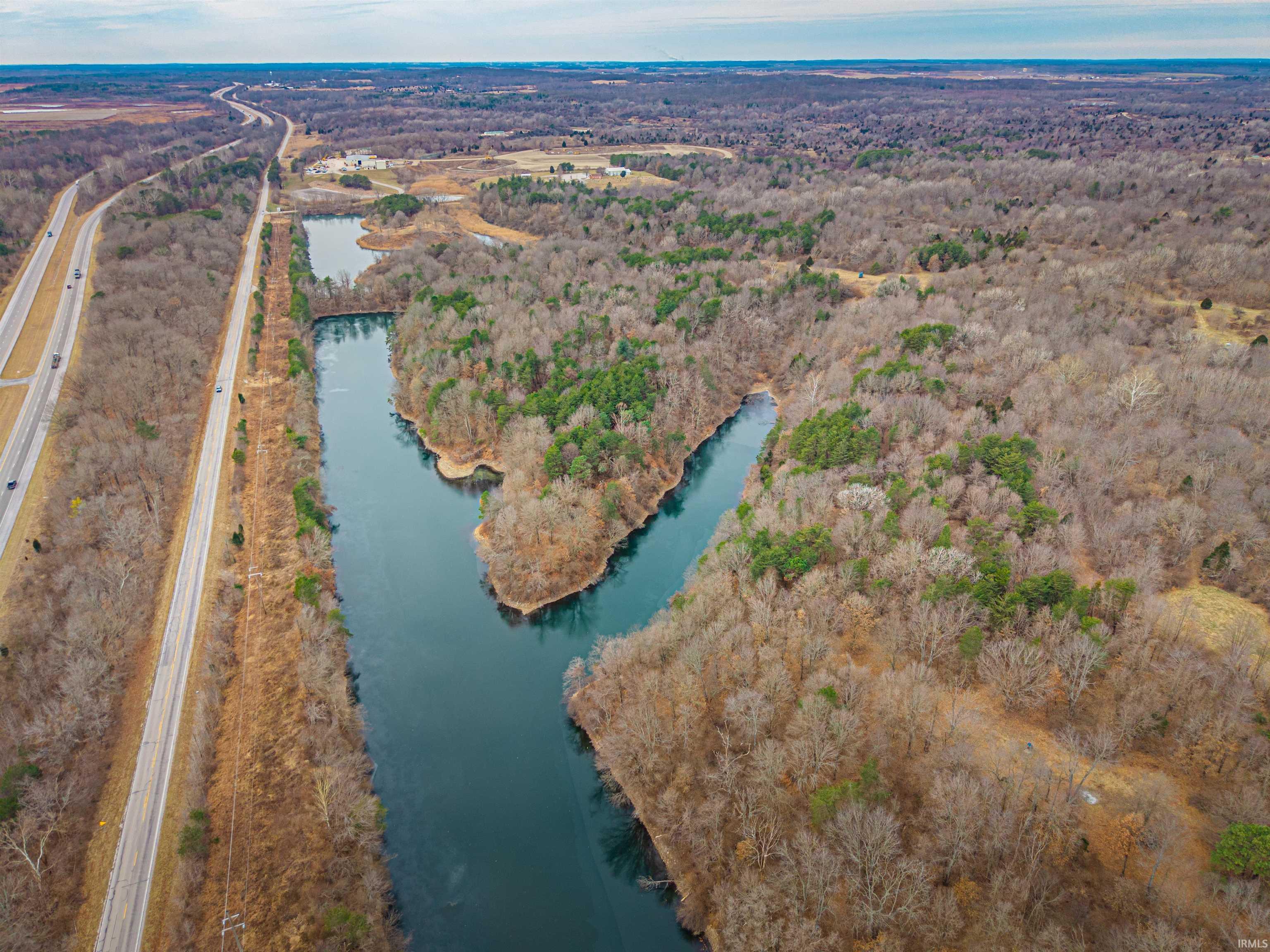 Image 2: Aerial overview of property's location with a heavily wooded area and a nearby body of water, Aerial View Image 2: Aerial overview of property's location with a heavily wooded area and a nearby body of water, Aerial View