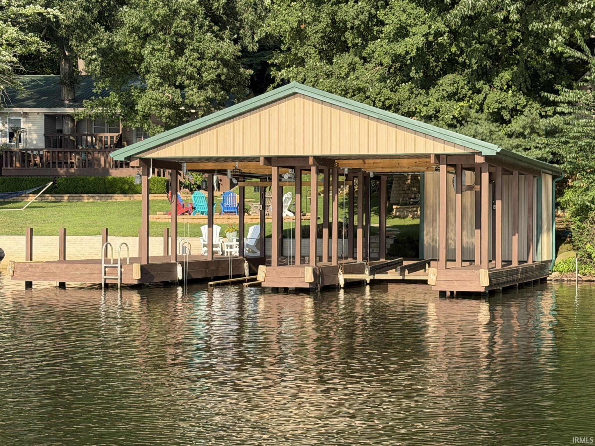 Image 3: Private boat dock featuring a light beige metal exterior with a green roof, multiple boat slips, and an attached ladder for water access, Dock Image 3: Private boat dock featuring a light beige metal exterior with a green roof, multiple boat slips, and an attached ladder for water access, Dock