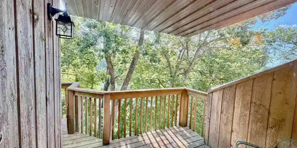 Image 2: Wood-plank exterior featuring a metal-paneled ceiling, wood deck, and wood railings, Deck Image 2: Wood-plank exterior featuring a metal-paneled ceiling, wood deck, and wood railings, Deck