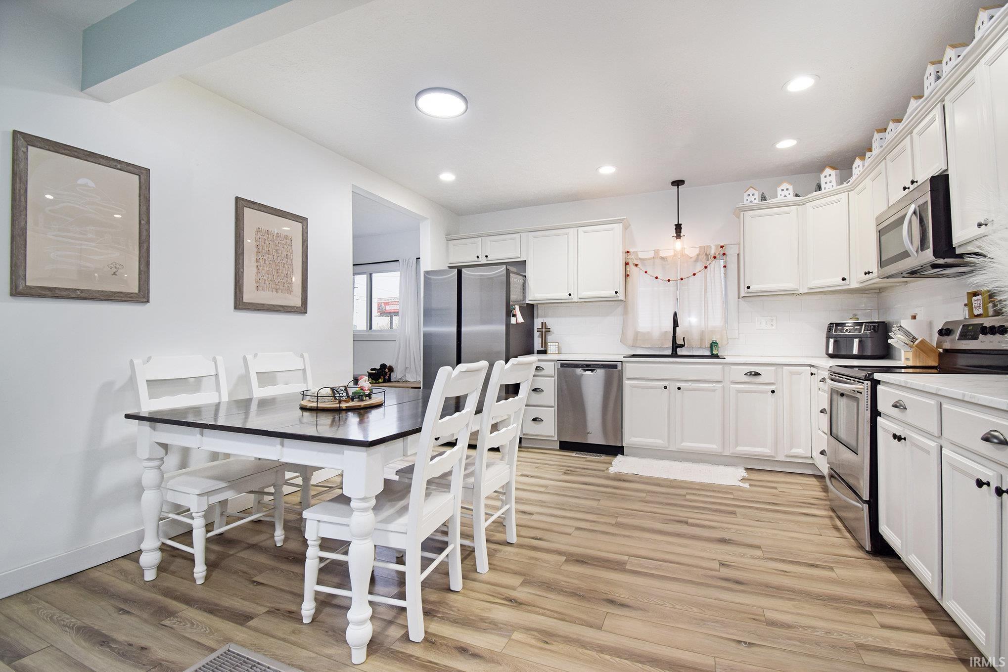 Image 3: Kitchen featuring appliances with stainless steel finishes, white cabinetry, hanging light fixtures, tasteful backsplash, and recessed lighting, Kitchen