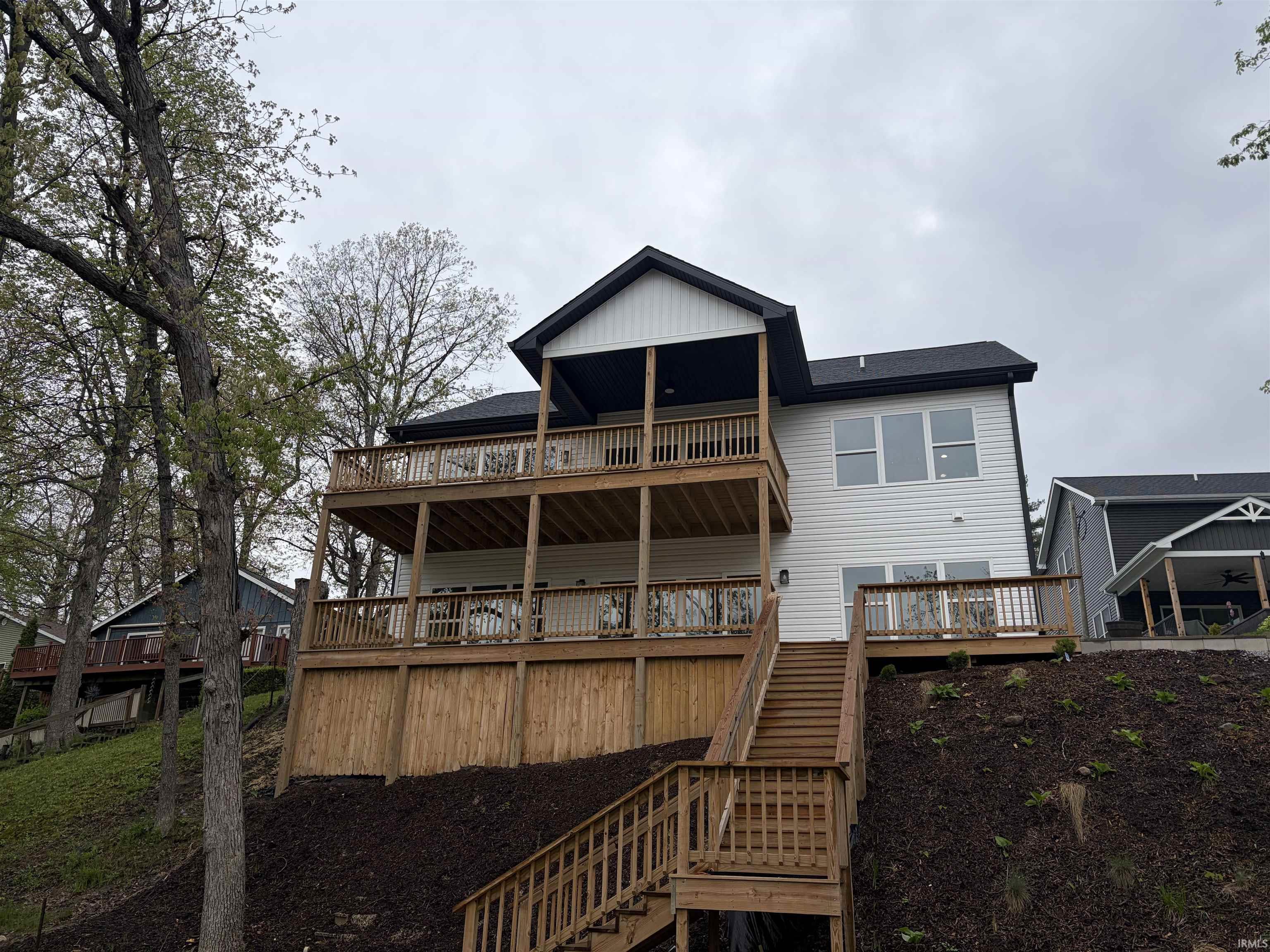 Image 2: Multi-level exterior featuring white vinyl siding and a dark shingle roof, Back Of Structure