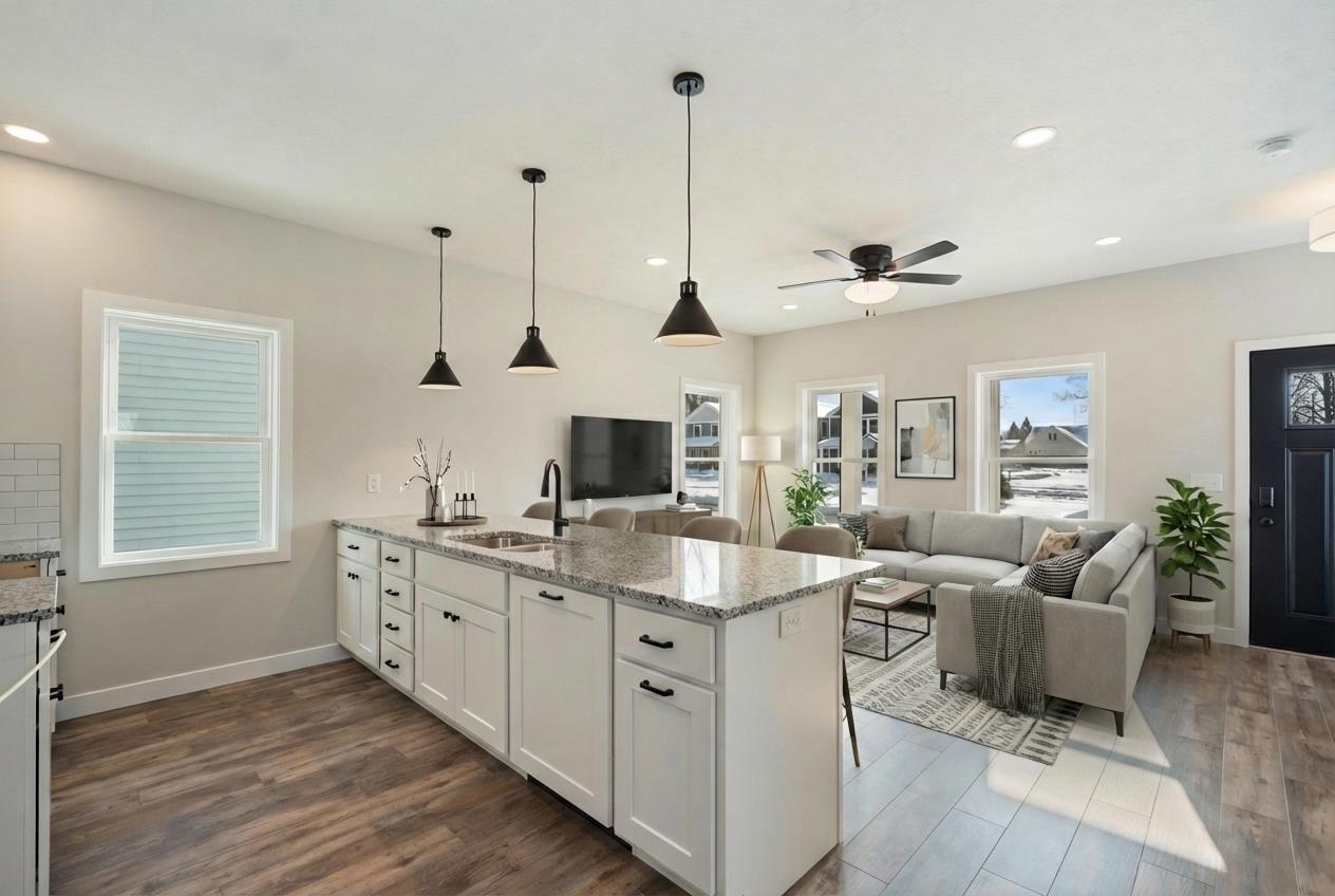 Image 1: Kitchen with white cabinetry, light stone counters, a peninsula, pendant lighting, and dark wood-style flooring, Kitchen and Living Area Image 1: Kitchen with white cabinetry, light stone counters, a peninsula, pendant lighting, and dark wood-style flooring, Kitchen and Living Area