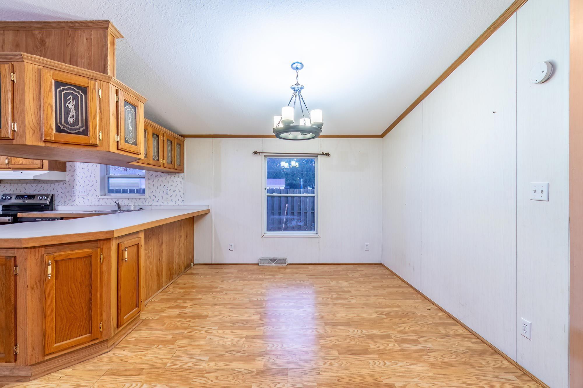 Image 3: Kitchen featuring brown cabinets, light wood-type flooring, light countertops, ornamental molding, and a peninsula, Kitchen Image 3: Kitchen featuring brown cabinets, light wood-type flooring, light countertops, ornamental molding, and a peninsula, Kitchen