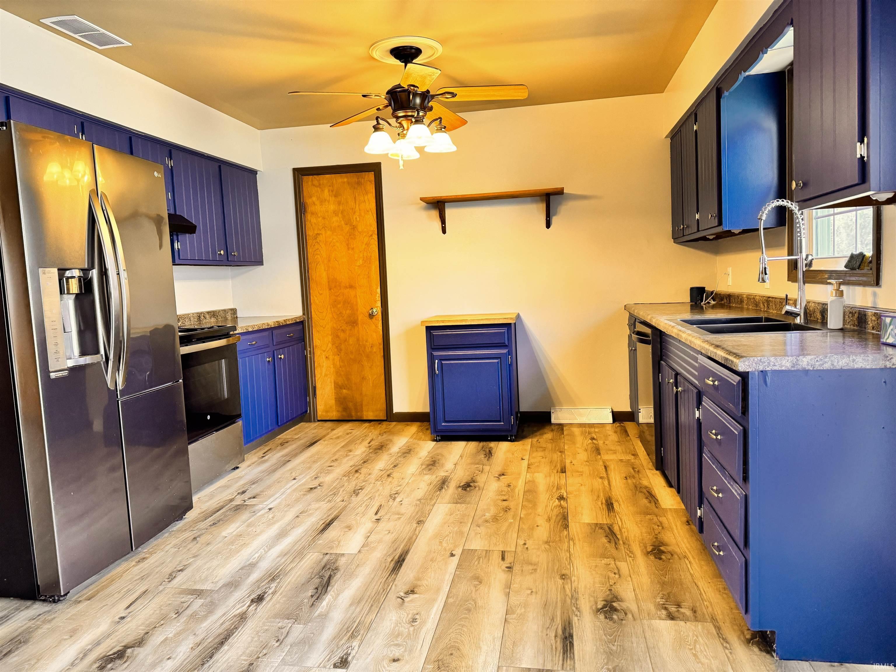 Image 2: Kitchen featuring stainless steel appliances, light wood-style flooring, ceiling fan, open shelves, and blue cabinets, Kitchen Image 2: Kitchen featuring stainless steel appliances, light wood-style flooring, ceiling fan, open shelves, and blue cabinets, Kitchen