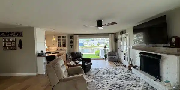 Image 1: Living area with light wood finished floors, a ceiling fan, a fireplace, and a textured ceiling, Living Room Image 1: Living area with light wood finished floors, a ceiling fan, a fireplace, and a textured ceiling, Living Room