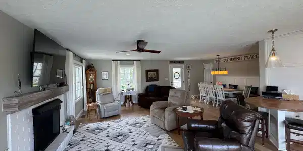 Image 3: Living area featuring a brick fireplace, light wood-style floors, ceiling fan, and a textured ceiling, Living Room Image 3: Living area featuring a brick fireplace, light wood-style floors, ceiling fan, and a textured ceiling, Living Room