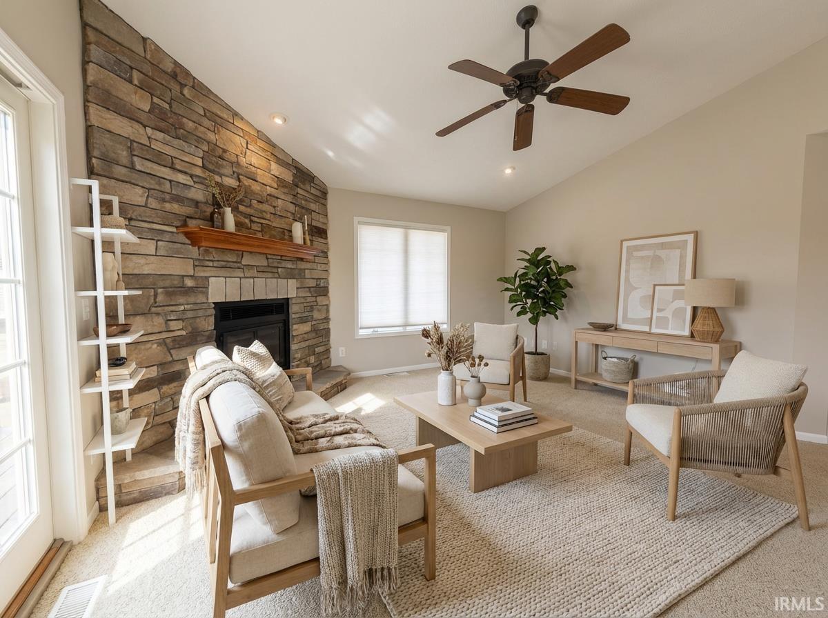 Image 2: Living room with lofted ceiling, light colored carpet, a stone fireplace, and ceiling fan, Virtually Staged
