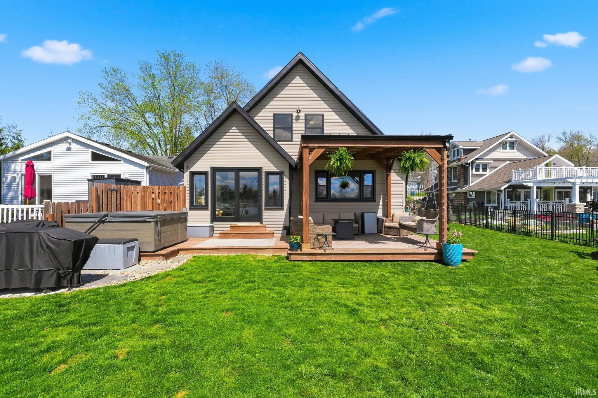 Image 0: Back of house with a hot tub, a wooden deck, a fenced backyard, and an outdoor living space, Back Of Structure
