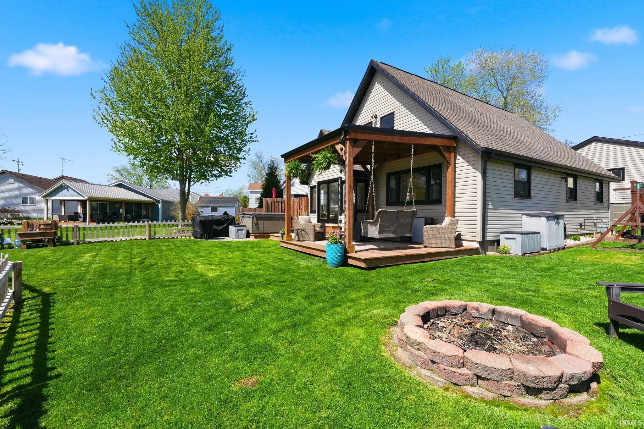 Image 1: Back of house with a fire pit, a deck, a shingled roof, and a hot tub, Back Of Structure