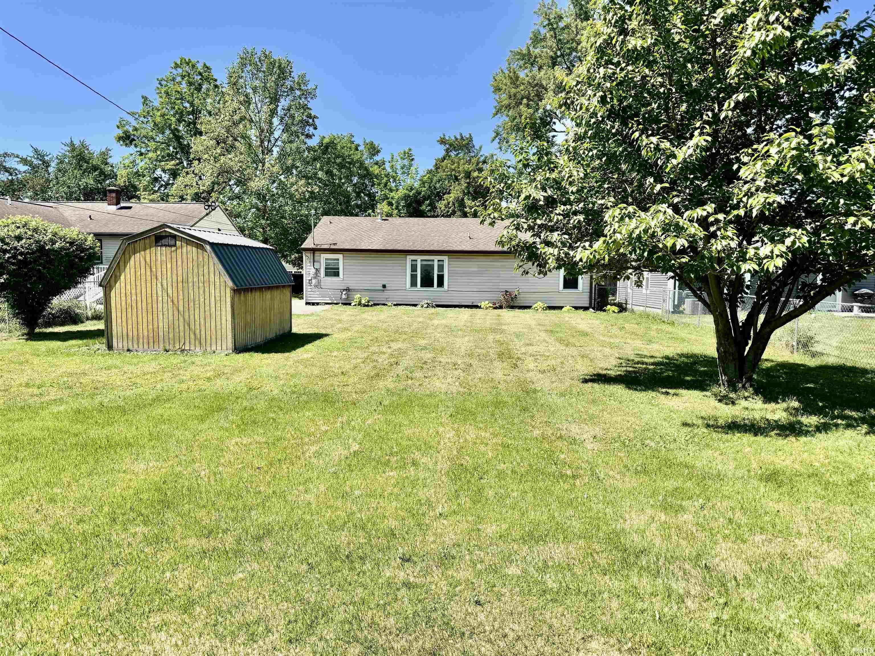 Image 1: Expansive backyard featuring a manicured lawn, a detached storage shed with a metal roof, and a mature shade tree, Back Of Structure Image 1: Expansive backyard featuring a manicured lawn, a detached storage shed with a metal roof, and a mature shade tree, Back Of Structure