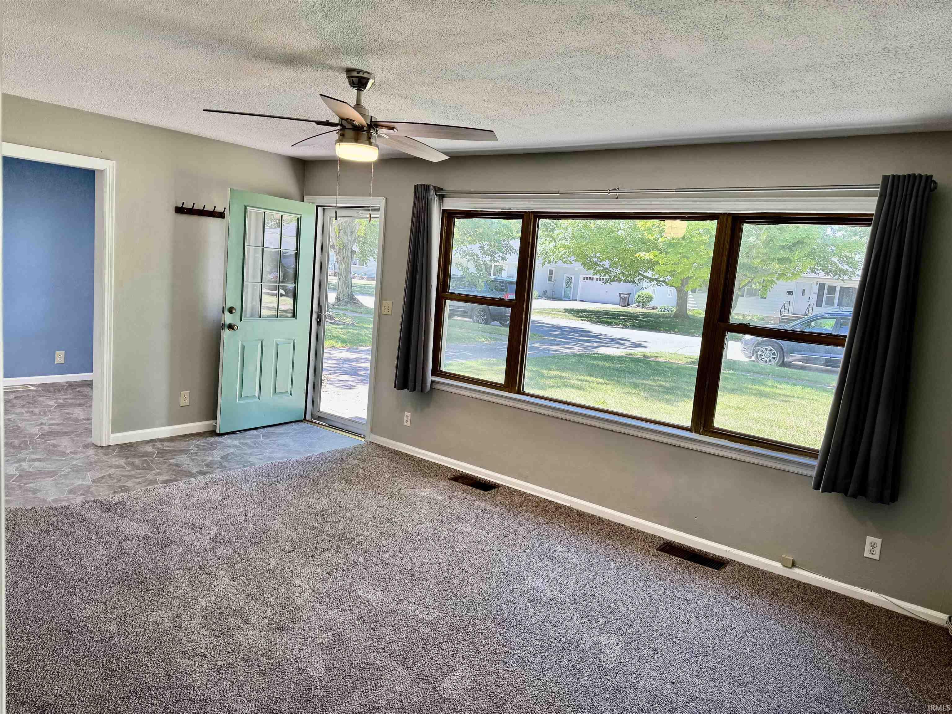 Image 2: Living area with grey carpeting, light grey walls, and a multi-pane front door, Entrance Foyer Image 2: Living area with grey carpeting, light grey walls, and a multi-pane front door, Entrance Foyer