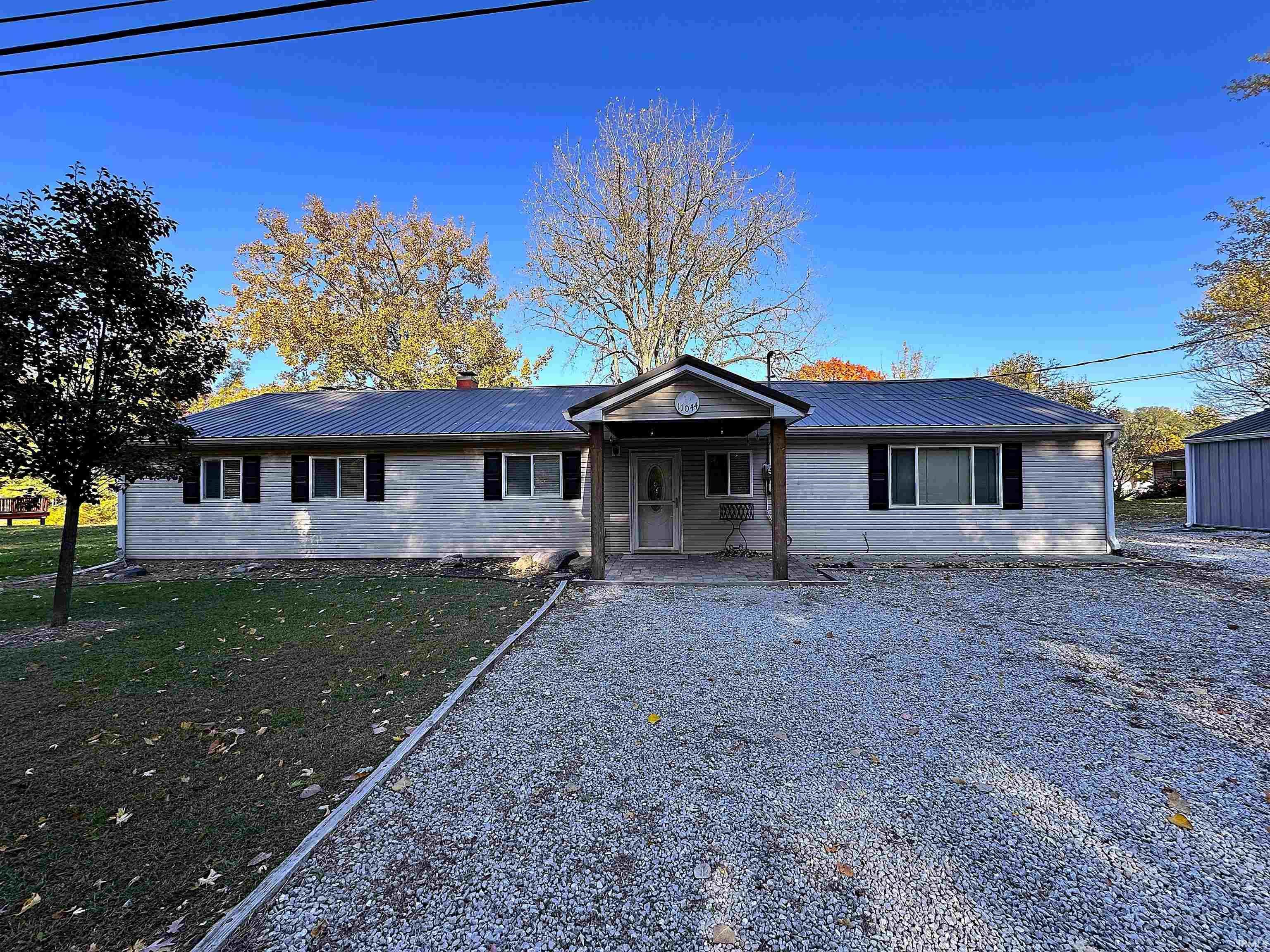 Image 1: Ranch-style house with a metal roof, a chimney, and a patio, Front Of Structure