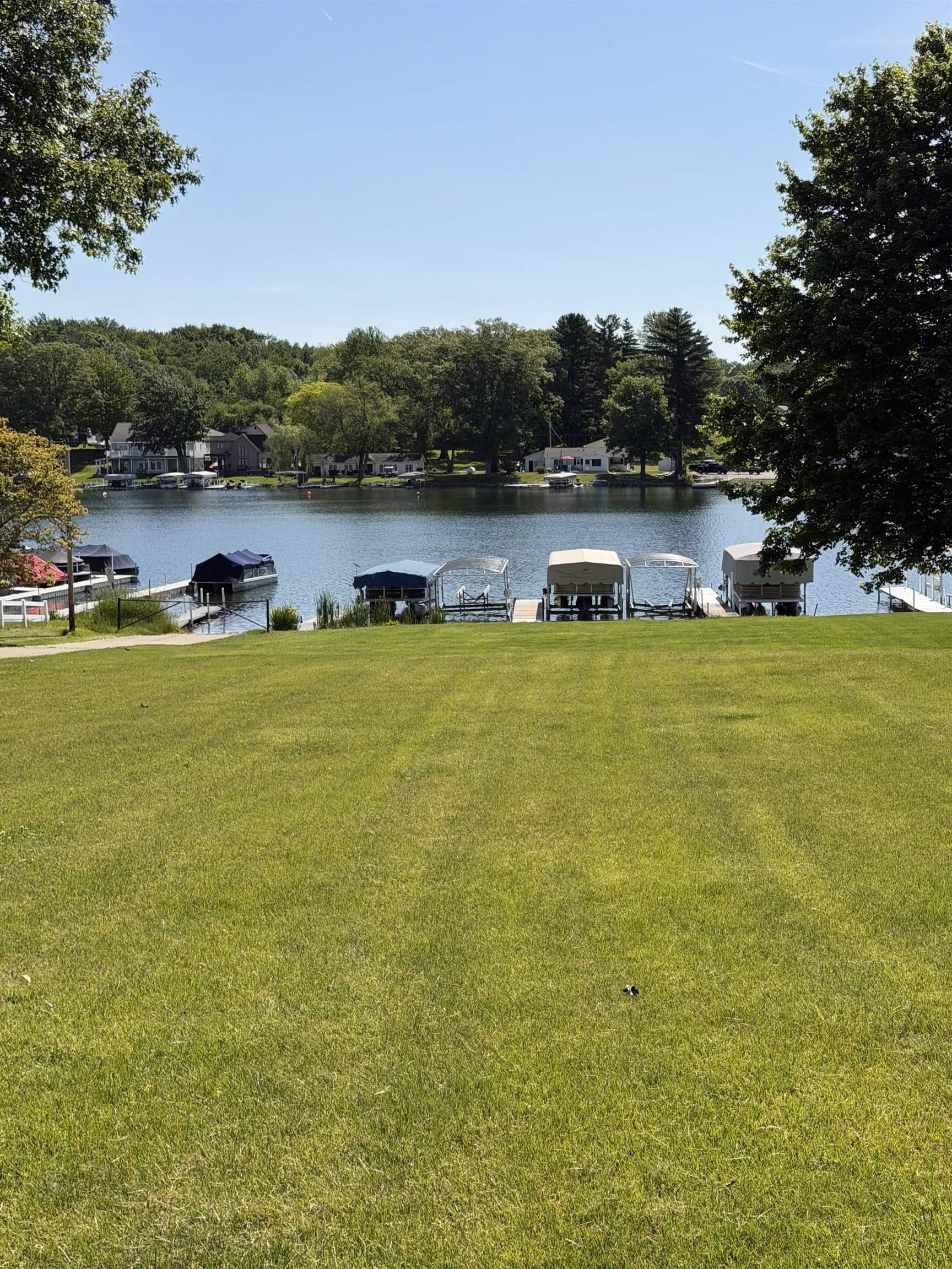 Image 3: Expansive association lawn descending to a large lake with multiple boat slips and docks, association access