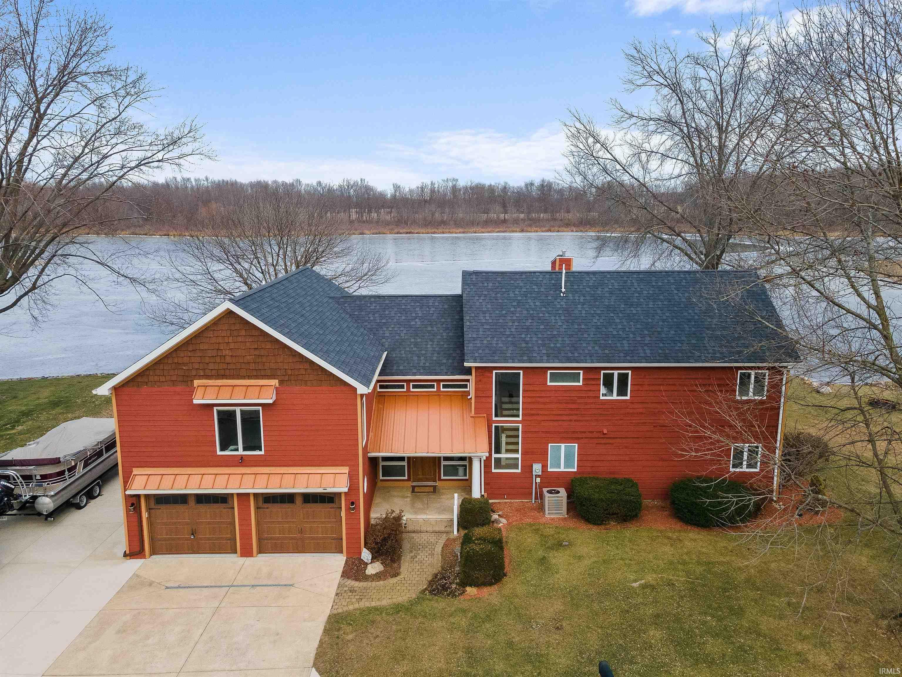 Image 0: Waterfront property featuring a red exterior with cedar shake accents and a copper-colored metal roof entry, Front Of Structure