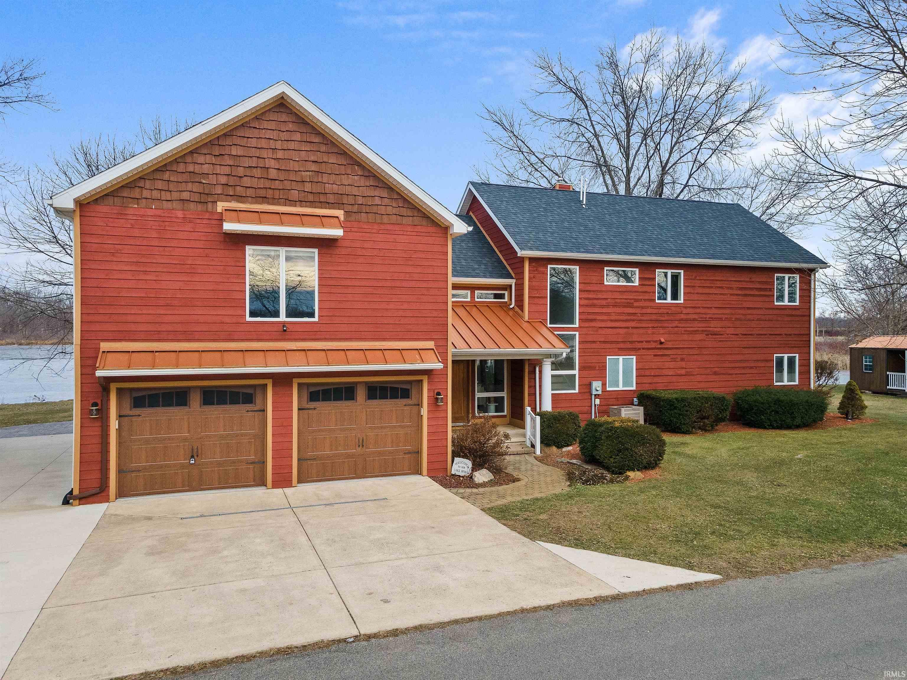 Image 3: Red siding exterior with a two-car garage featuring wood-finish doors, Front Of Structure