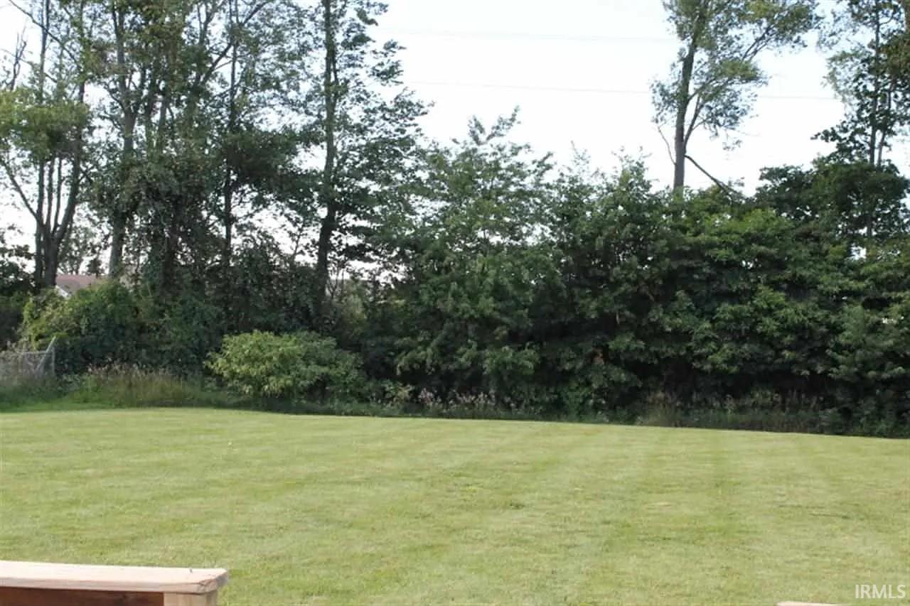 Image 2: Expansive green lawn framed by mature trees and natural landscaping, Yard