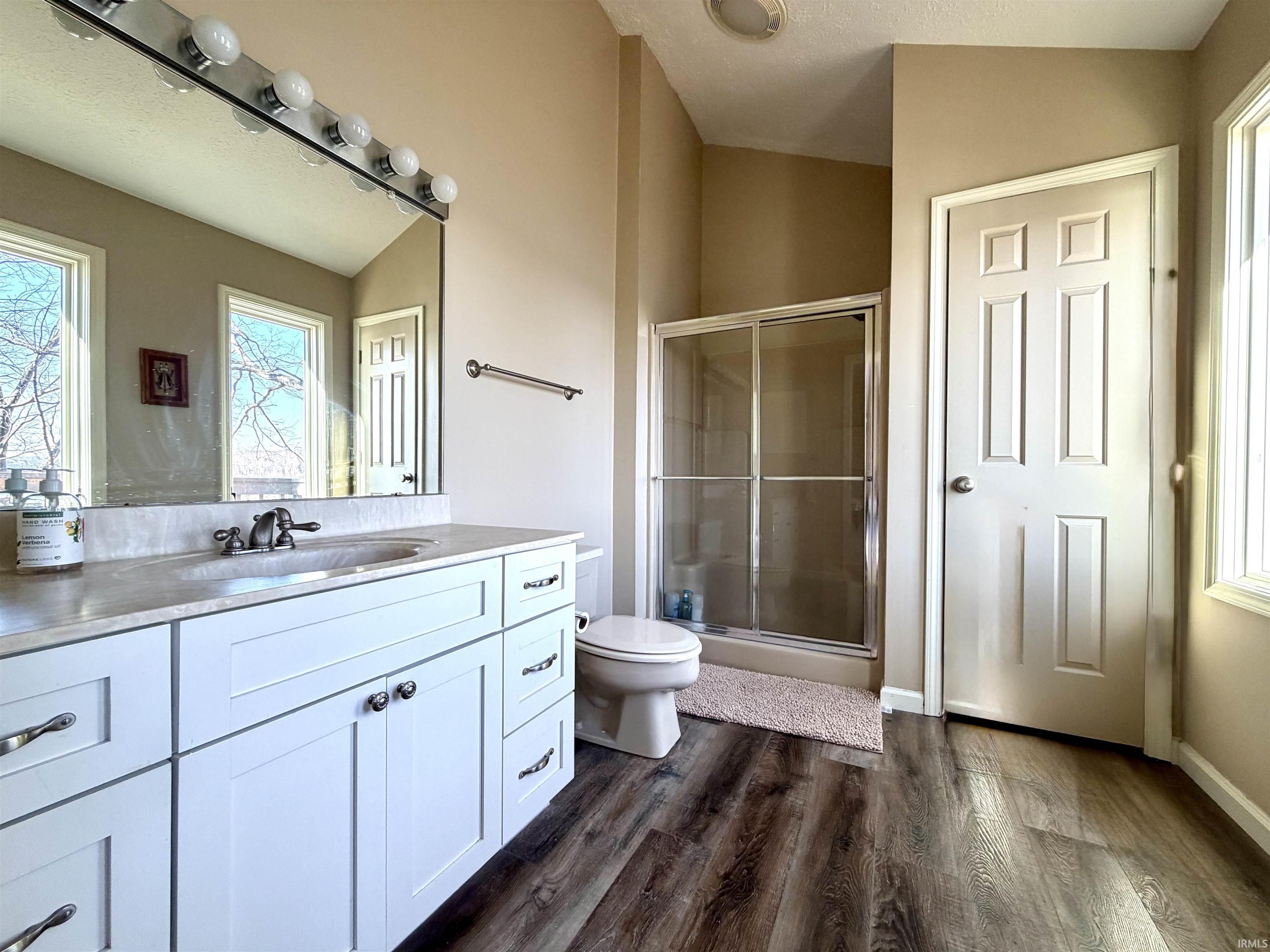 Image 2: Bathroom featuring vanity, a shower stall, dark wood-type flooring, and lofted ceiling, Bathroom