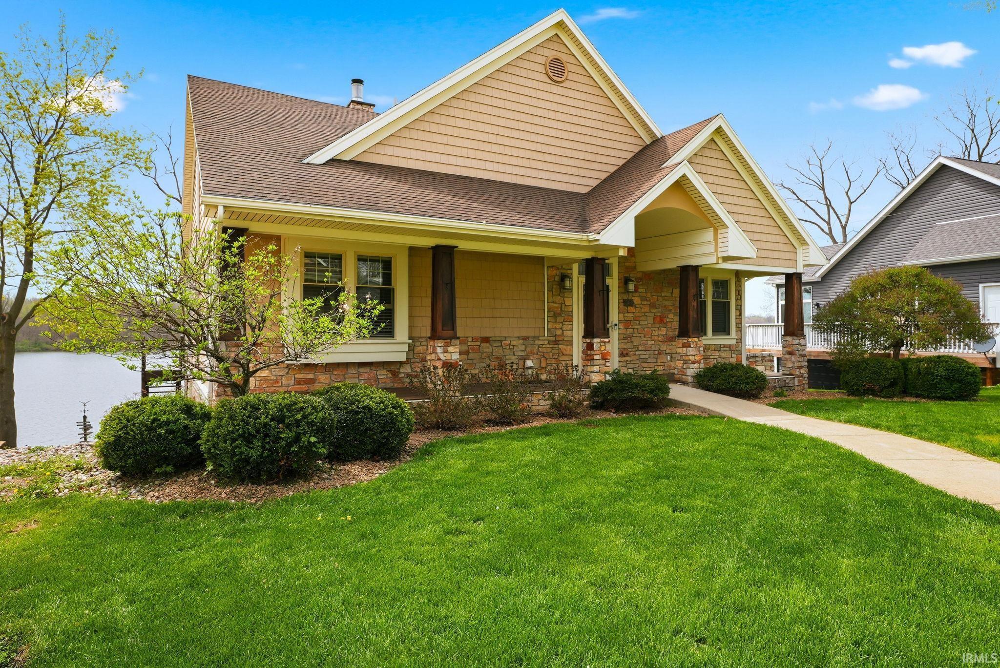 Image 3: View of front of house featuring roof with shingles, stone siding, a front lawn, and covered porch, Front Of Structure