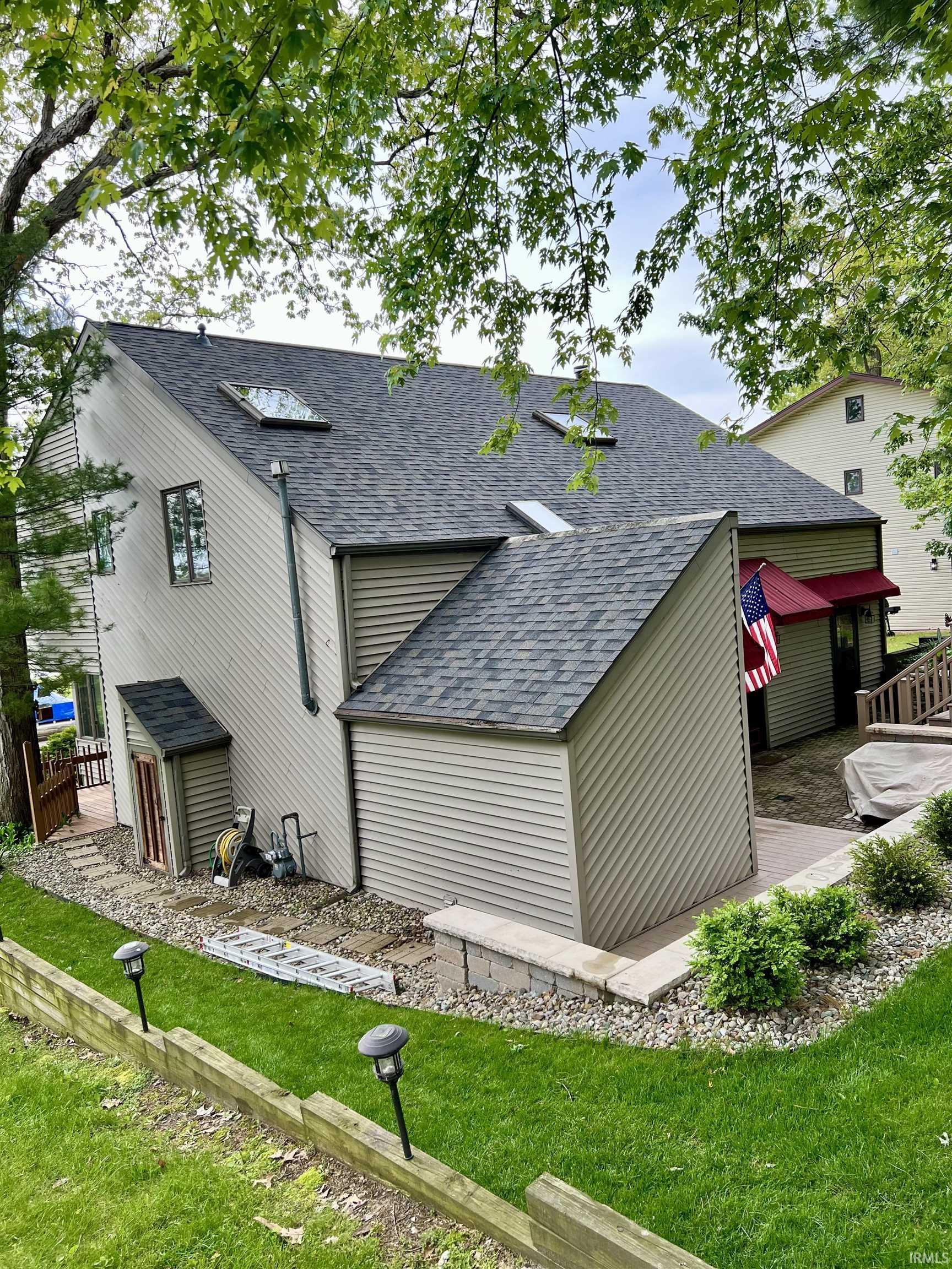 Image 2: Multi-level residence featuring a gray shingle roof with multiple skylights, Back Of Structure Image 2: Multi-level residence featuring a gray shingle roof with multiple skylights, Back Of Structure