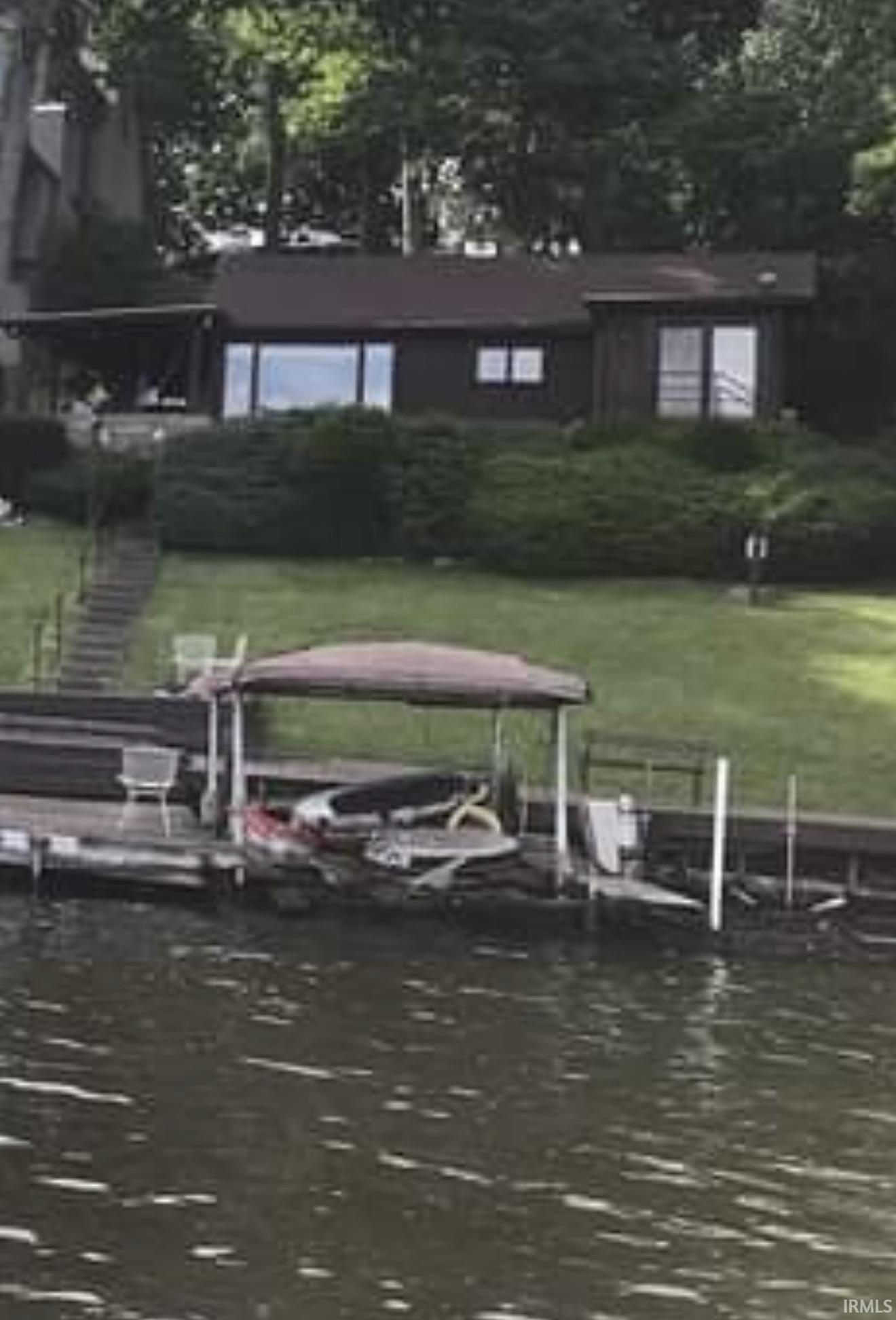Image 0: Dock area with a water view, boat lift, and a yard, Dock