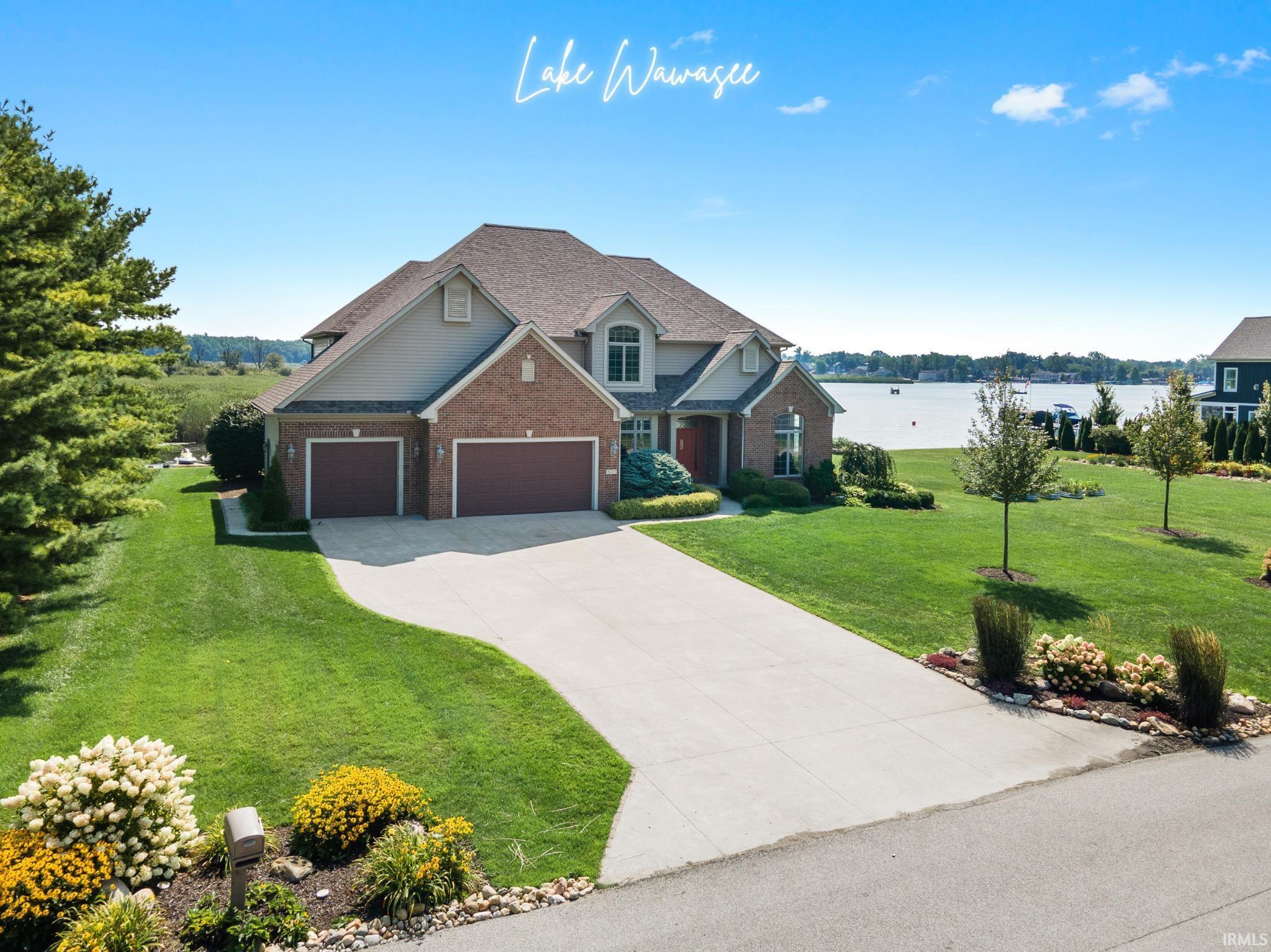 Image 0: View of front of home featuring brick siding, concrete driveway, a front yard, and a water view, Front Of Structure
