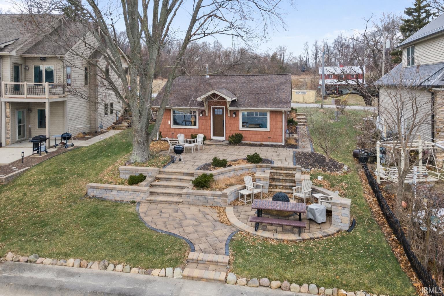 Image 0: View of front of property featuring a patio, a front yard, roof with shingles, and a fire pit, Front Of Structure