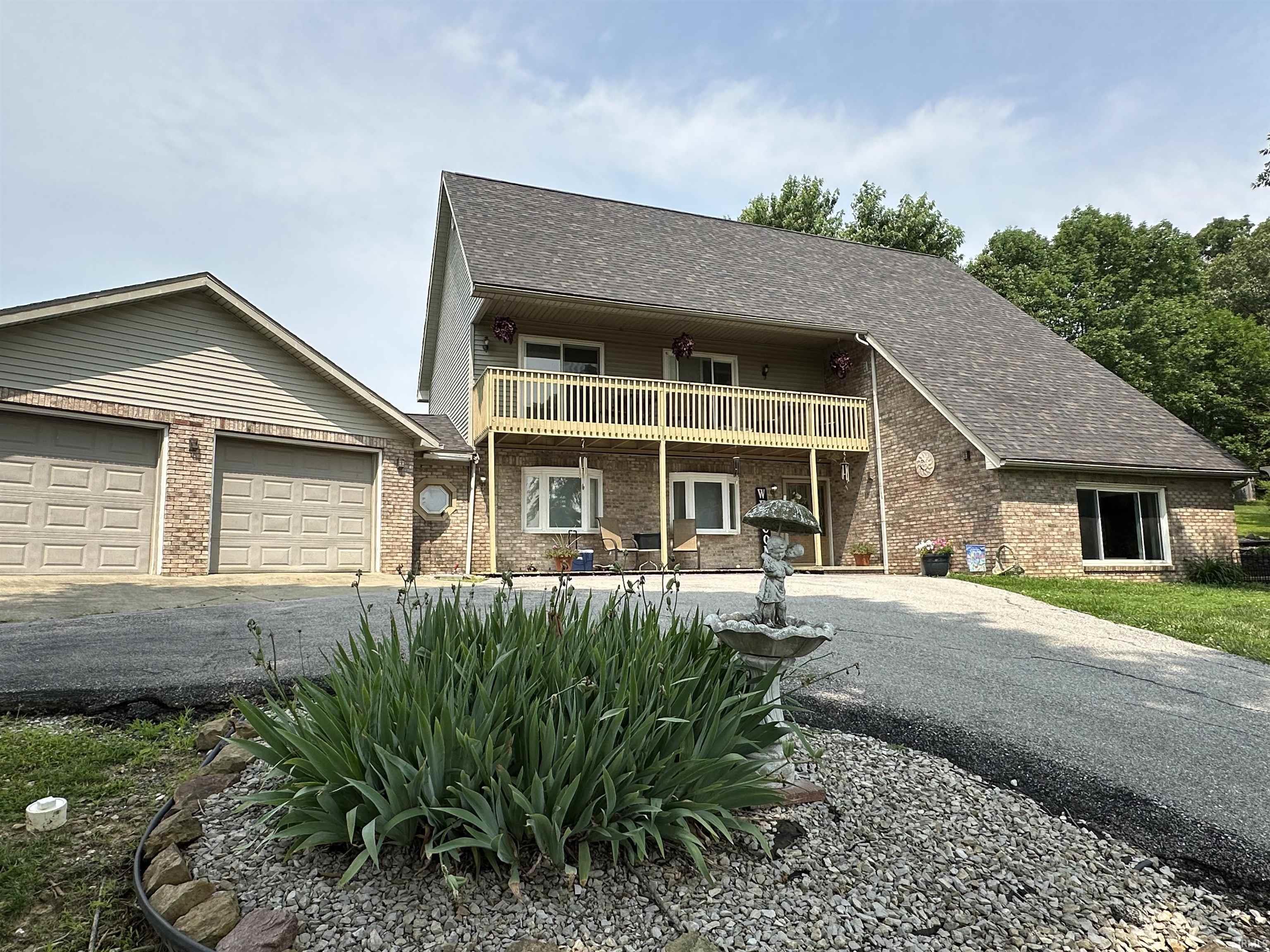 Image 0: View of front of house featuring a shingled roof, driveway, brick siding, and a balcony, Front Of Structure