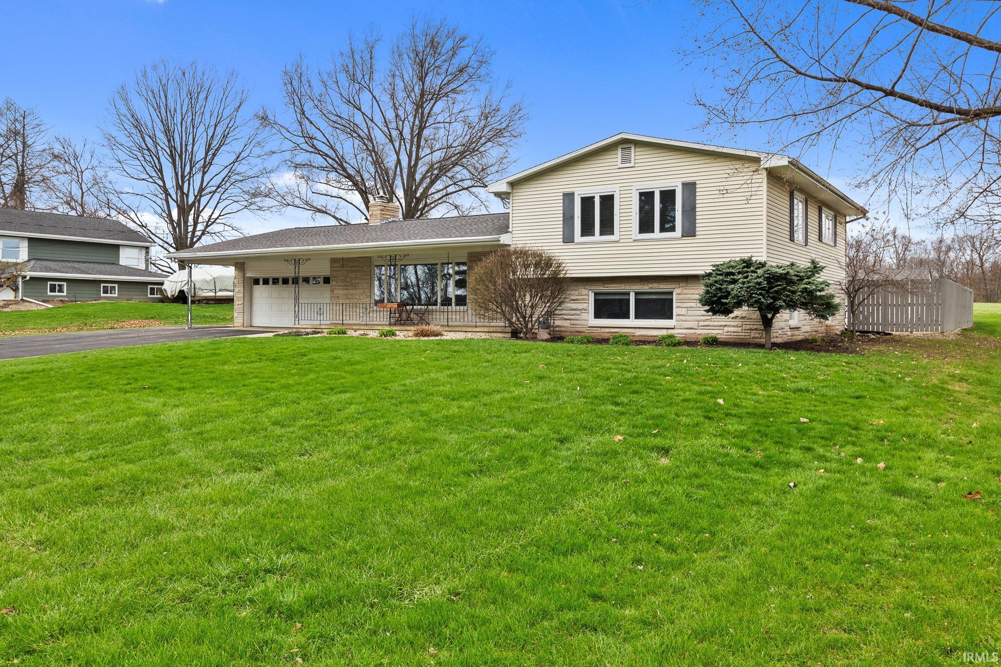 Image 1: Tri-level home featuring an attached garage, driveway, a chimney, and covered porch, Front Of Structure