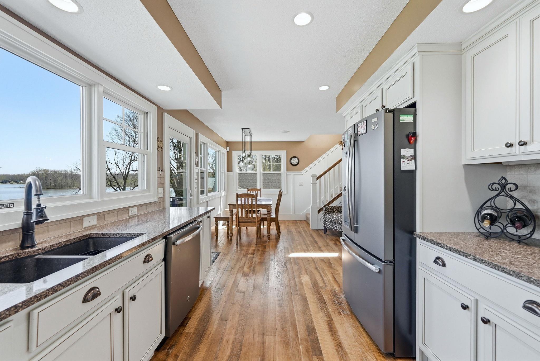 Image 3: Kitchen featuring white cabinetry, a double basin sink, stainless steel appliances, and wood-finish flooring, Kitchen