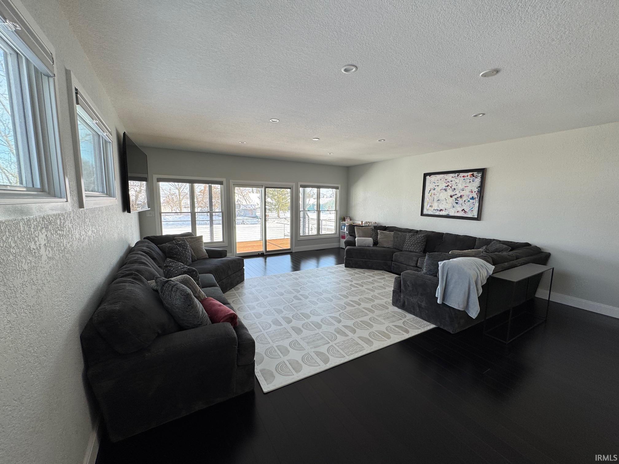 Image 1: Living area with wood finished floors, a textured ceiling, and a textured wall, Living Room