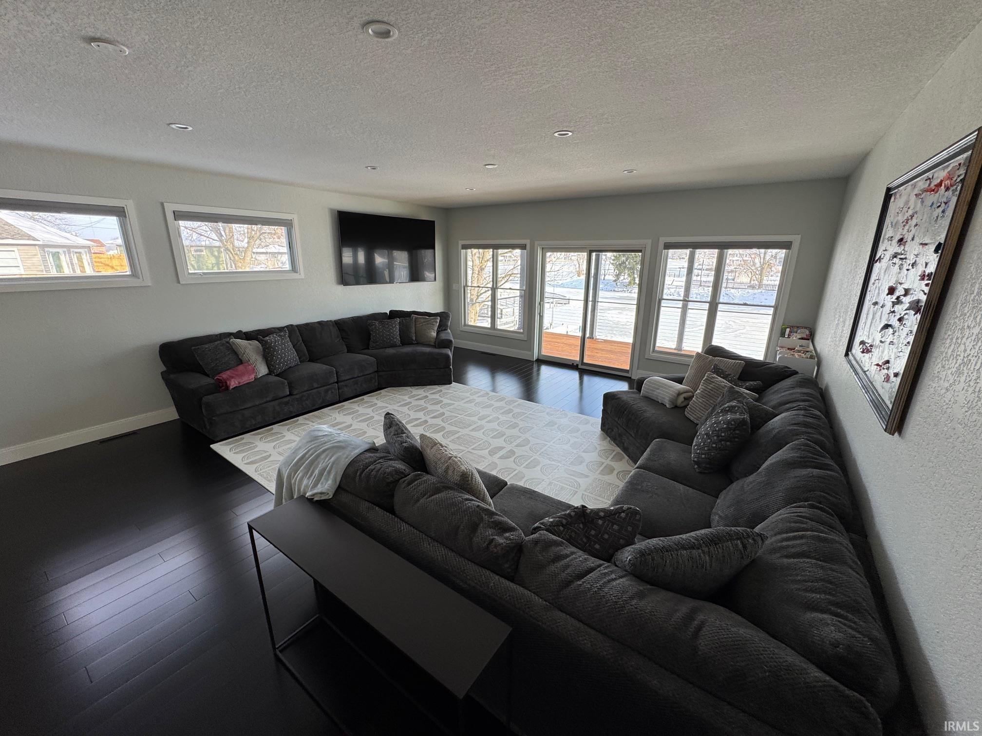 Image 2: Living room featuring dark wood-style flooring, a textured ceiling, and healthy amount of natural light, Living Room