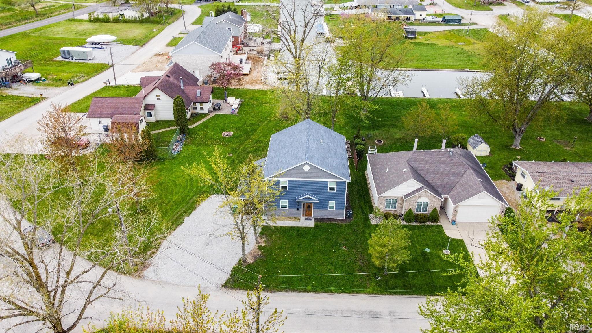 Image 3: Blue siding exterior with a light gray roof, set on a green lawn, Aerial View