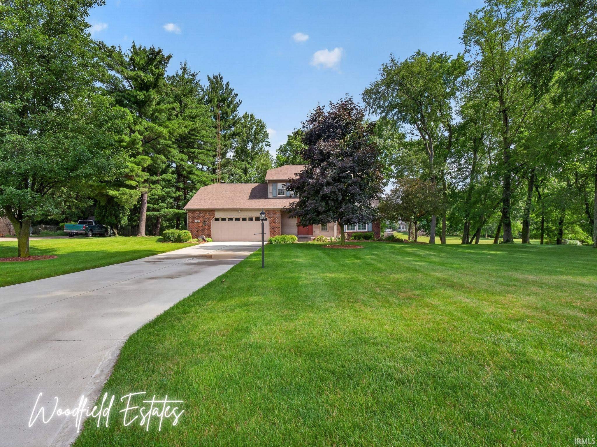 Image 0: Brick facade residence with an attached garage, a long concrete driveway, and a expansive green lawn, Front Of Structure