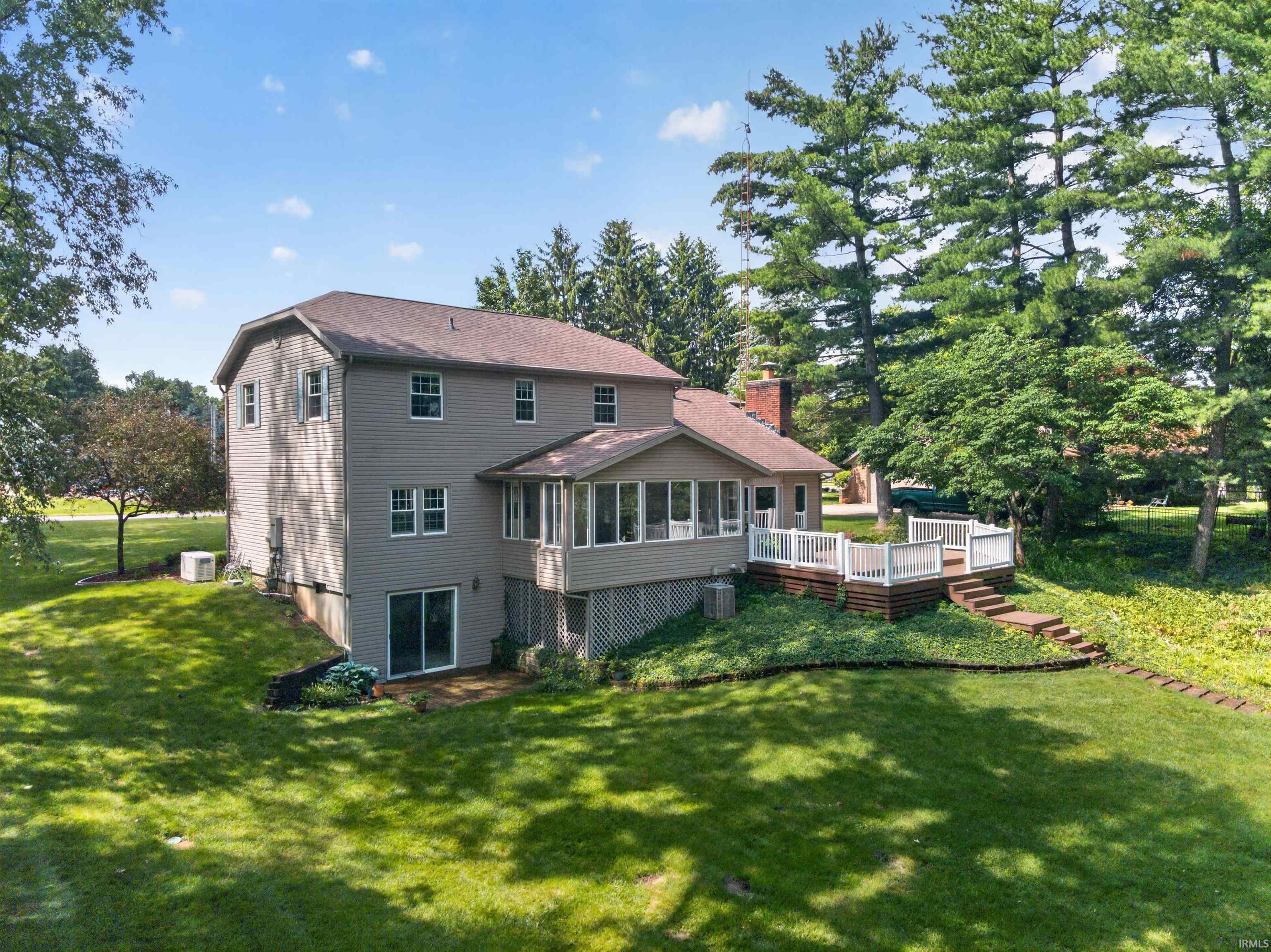 Image 1: Spacious rear exterior featuring a multi-level deck with white railings, a sunroom extension, and a walk-out lower level with sliding doors, Back Of Structure