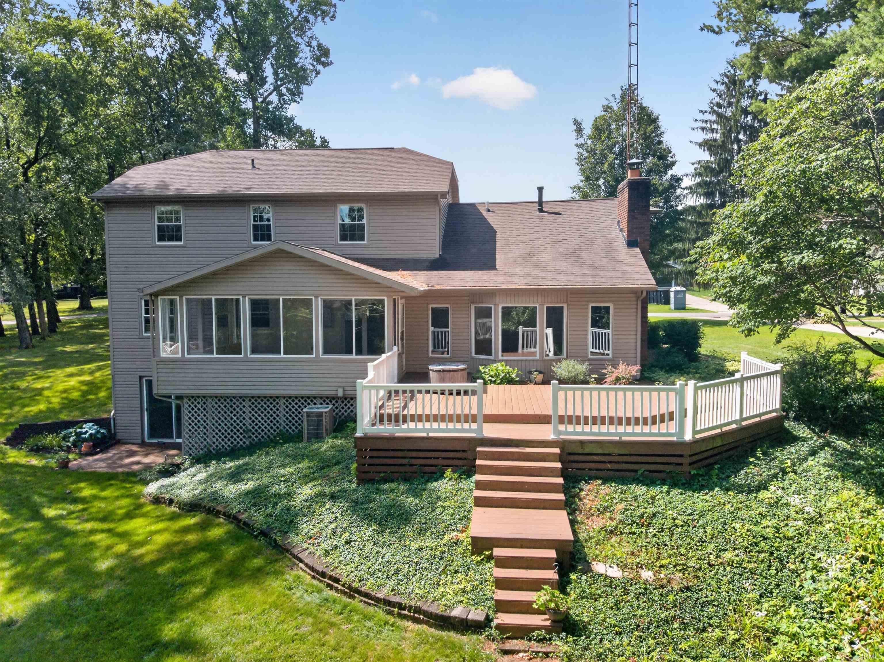 Image 2: Two-story residence featuring a large rear deck with white railing, a screened-in porch, and a lower-level walkout, Back Of Structure