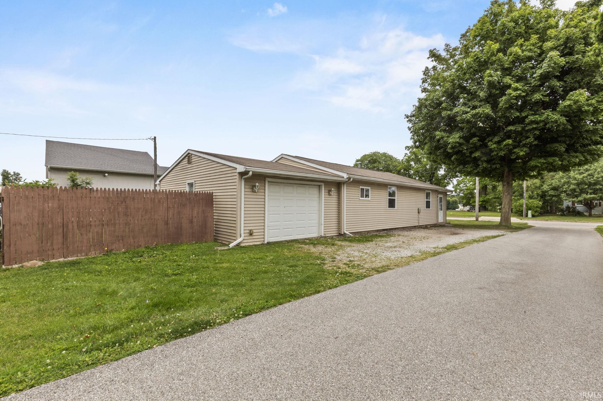 Image 0: Detached garage featuring a white overhead door and beige siding, Garage Image 0: Detached garage featuring a white overhead door and beige siding, Garage