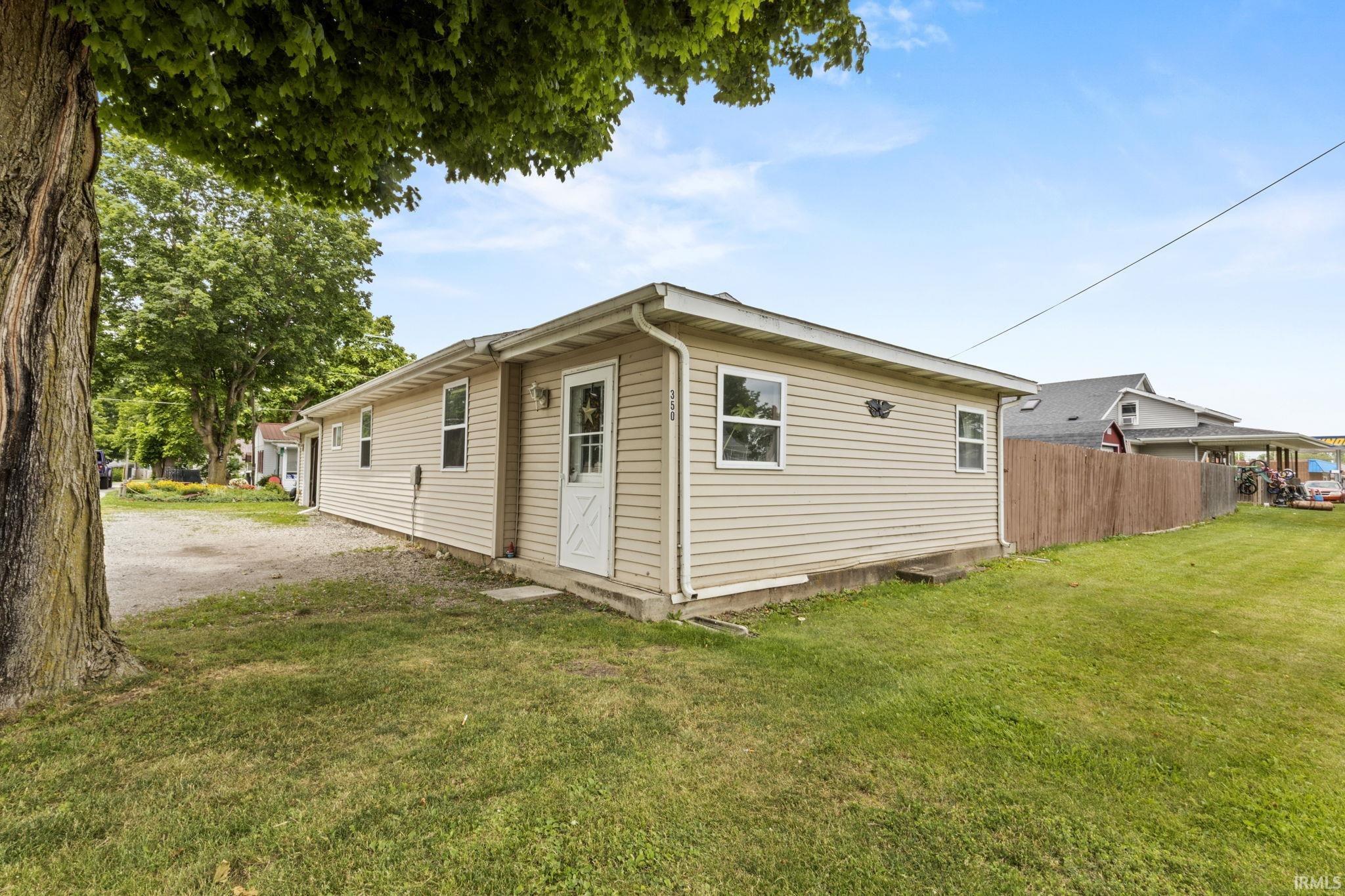 Image 2: Beige vinyl siding exterior with white trim, multiple windows, and a white paneled door, Back Of Structure Image 2: Beige vinyl siding exterior with white trim, multiple windows, and a white paneled door, Back Of Structure