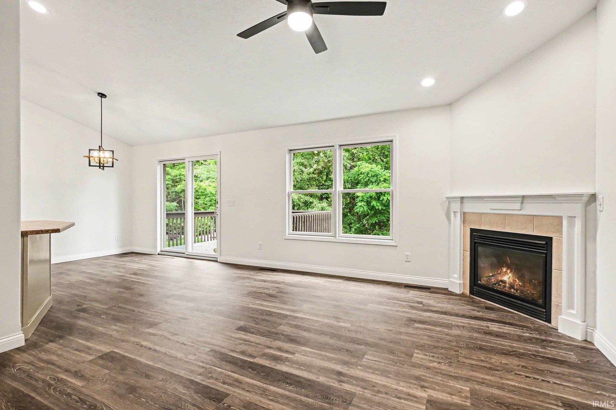 Image 3: Spacious interior featuring wood-finish flooring, a contemporary fireplace with a tile surround and white mantel, a ceiling fan, and recessed lighting, Living Room Image 3: Spacious interior featuring wood-finish flooring, a contemporary fireplace with a tile surround and white mantel, a ceiling fan, and recessed lighting, Living Room