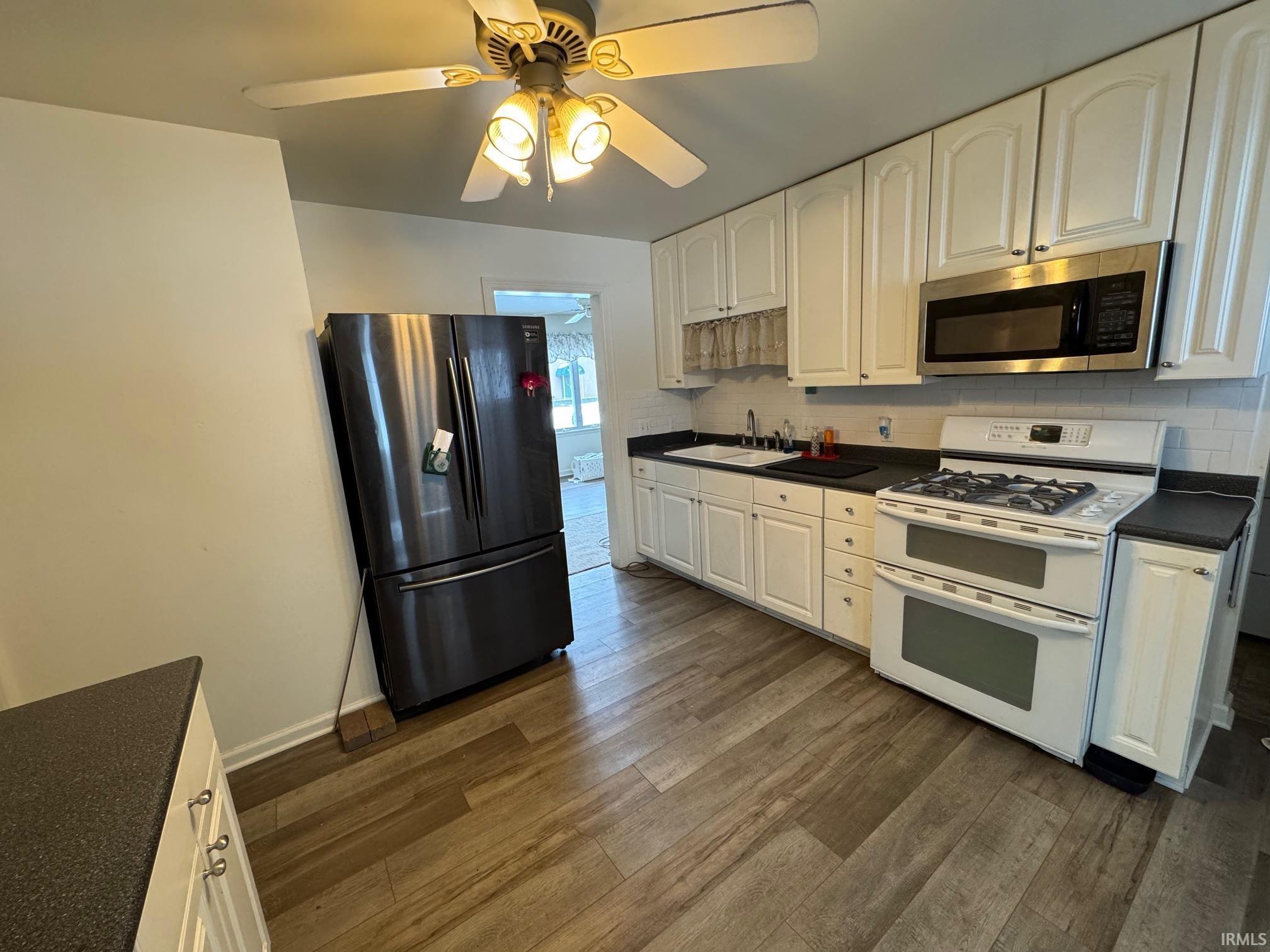 Image 1: Kitchen with dark countertops, double oven range, fridge with ice dispenser, and stainless steel microwave, Kitchen